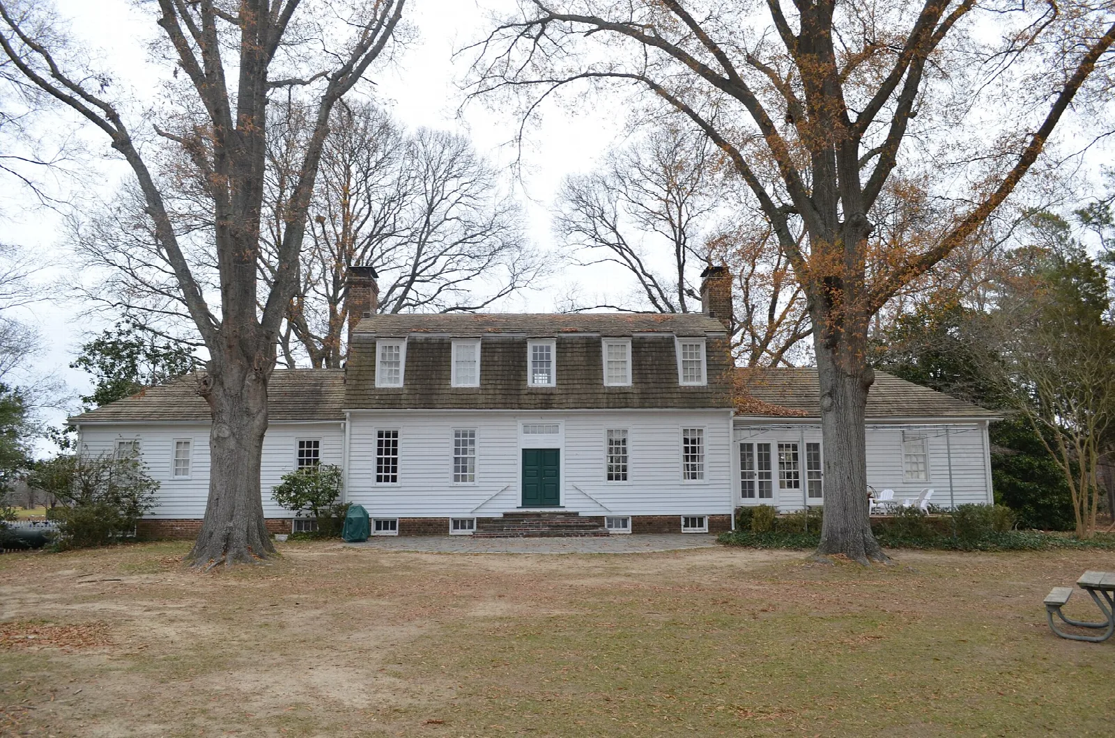 White two-story house with a gabled roof among bare trees