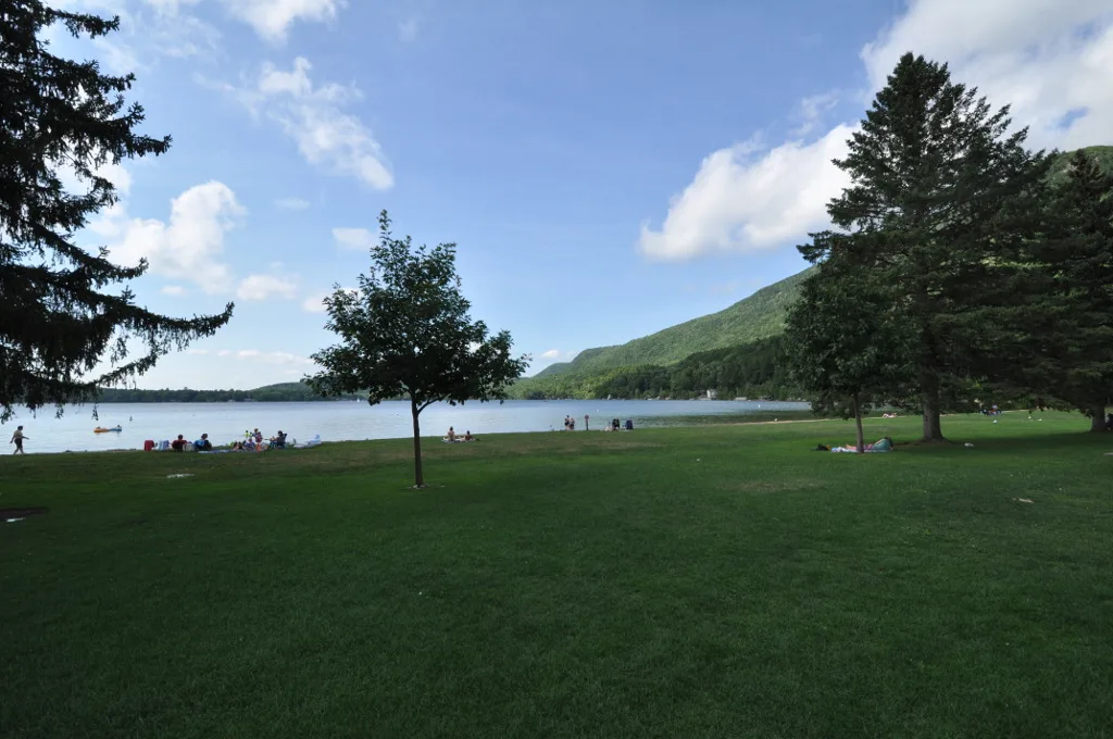 Grass lawn running down to Lake Dunmore, with tall trees and a green hill across the water
