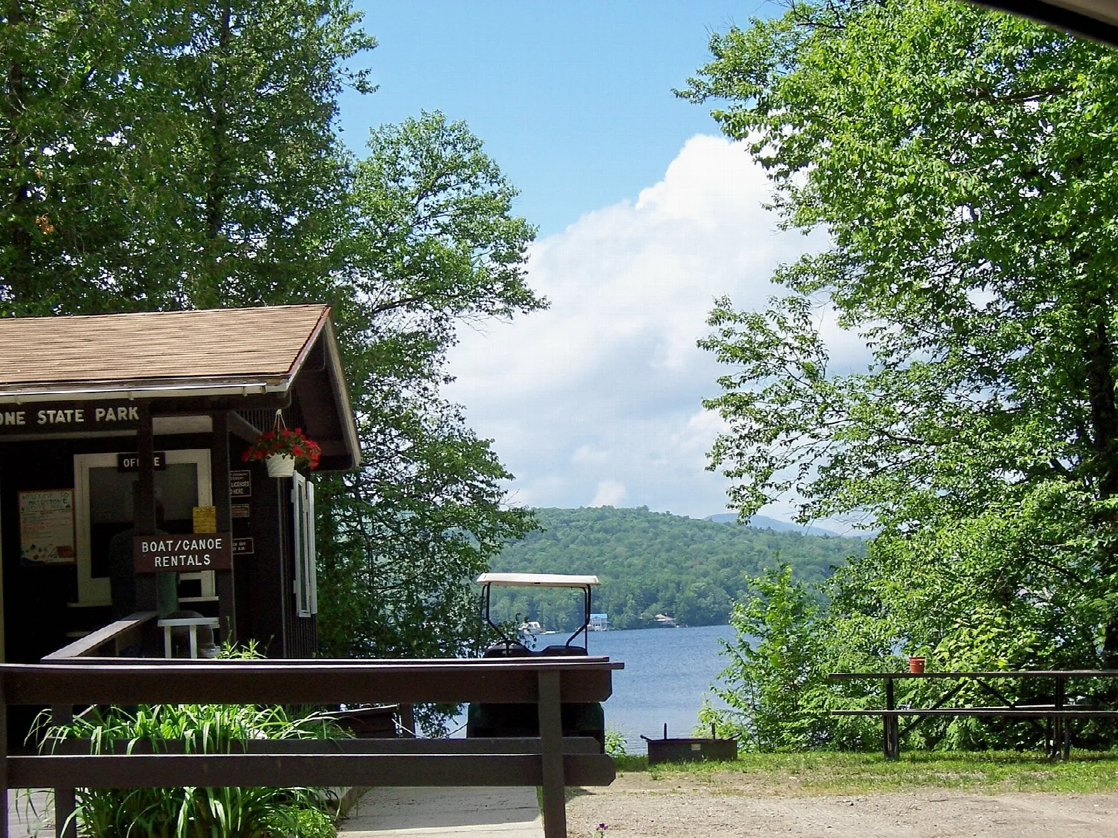Wooden boat rental building on a deck with trees and Maidstone Lake behind it