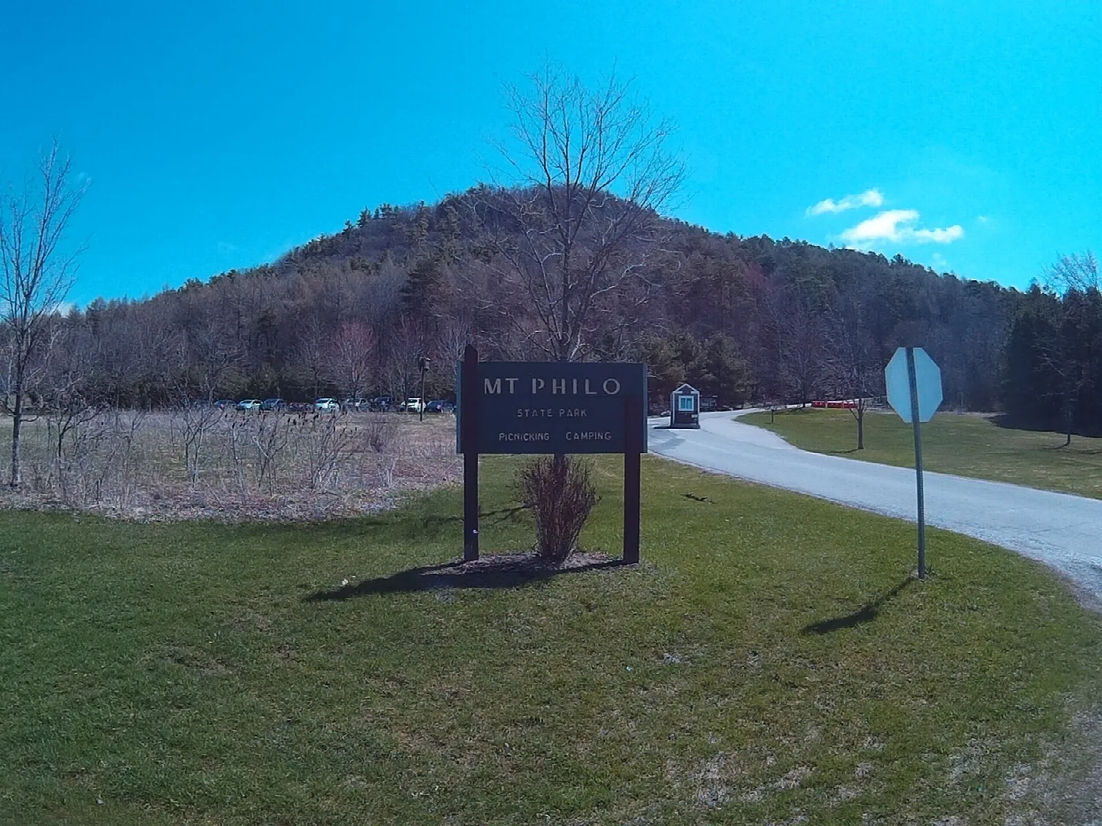 Wooded Mt. Philo rising behind a park sign and entrance road