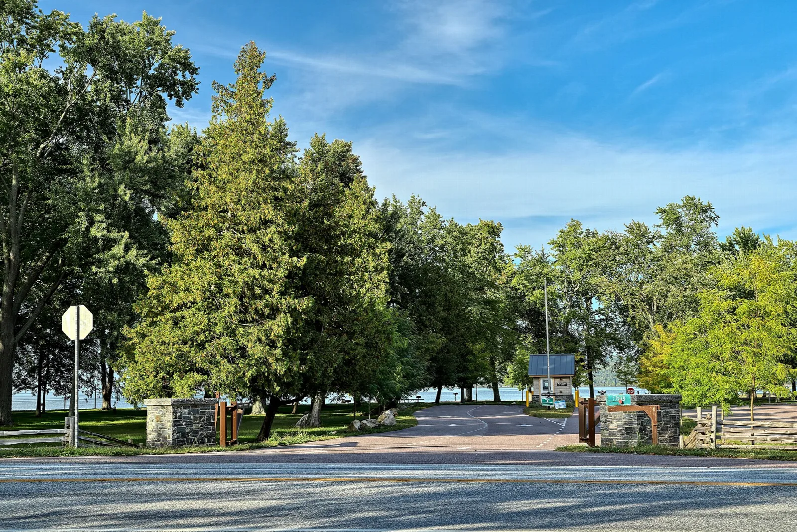 Park entrance with stone posts, trees and the lake in the distance