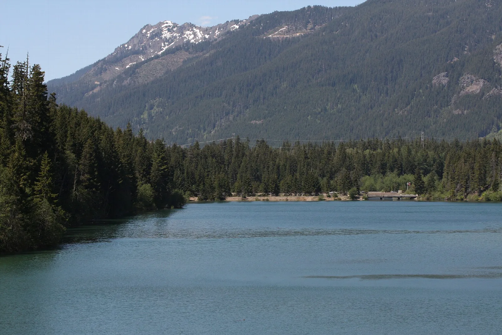 Calm lake below forested ridges and a mountain skyline