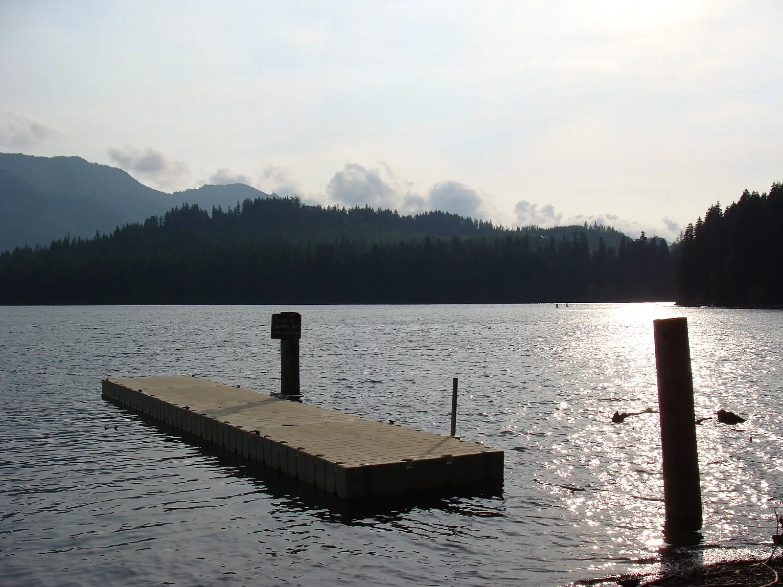 Floating dock on a still lake with forested hills beyond