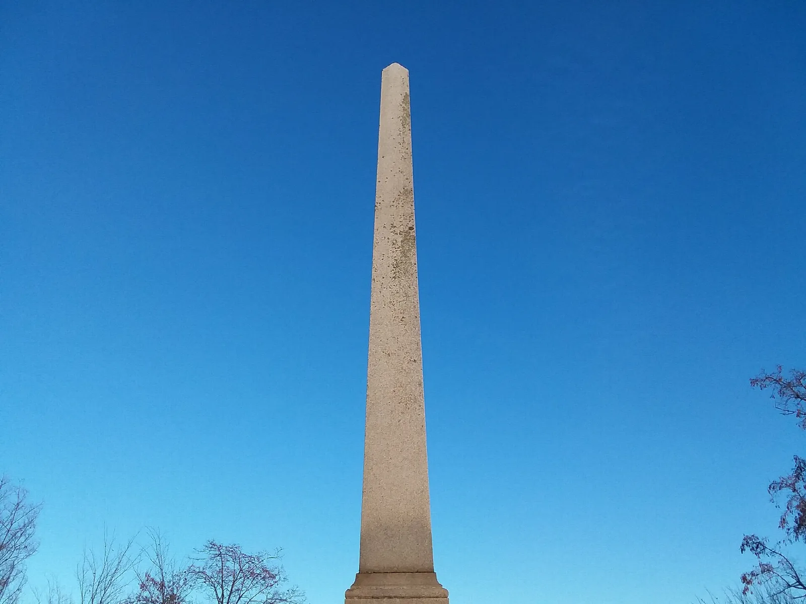 Slim stone obelisk against a clear blue sky