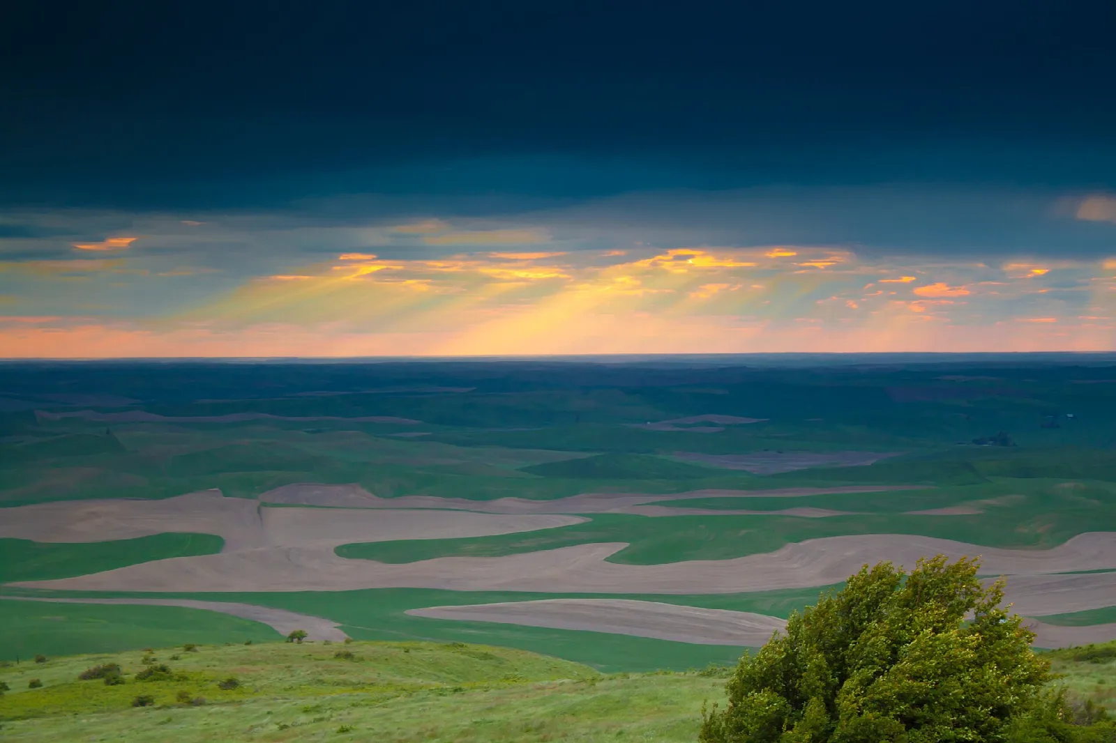 Orange sunset glow over distant fields seen from the butte