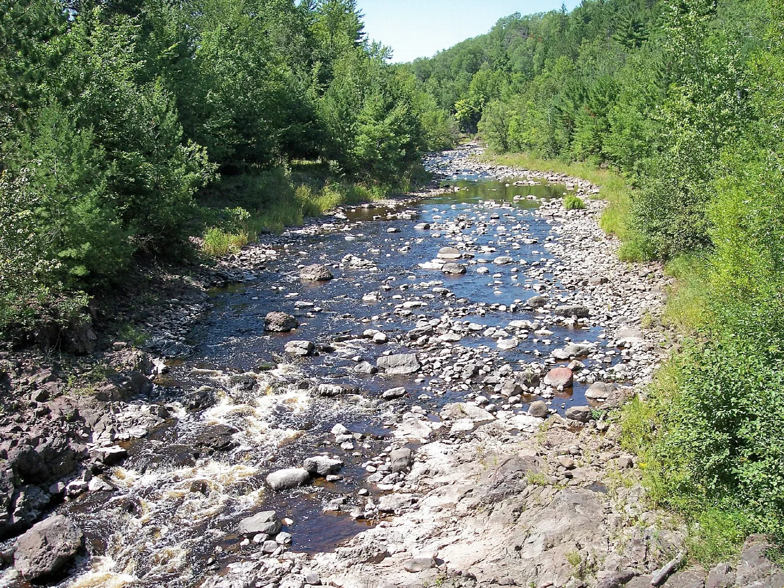 Rocky river running between green forested banks