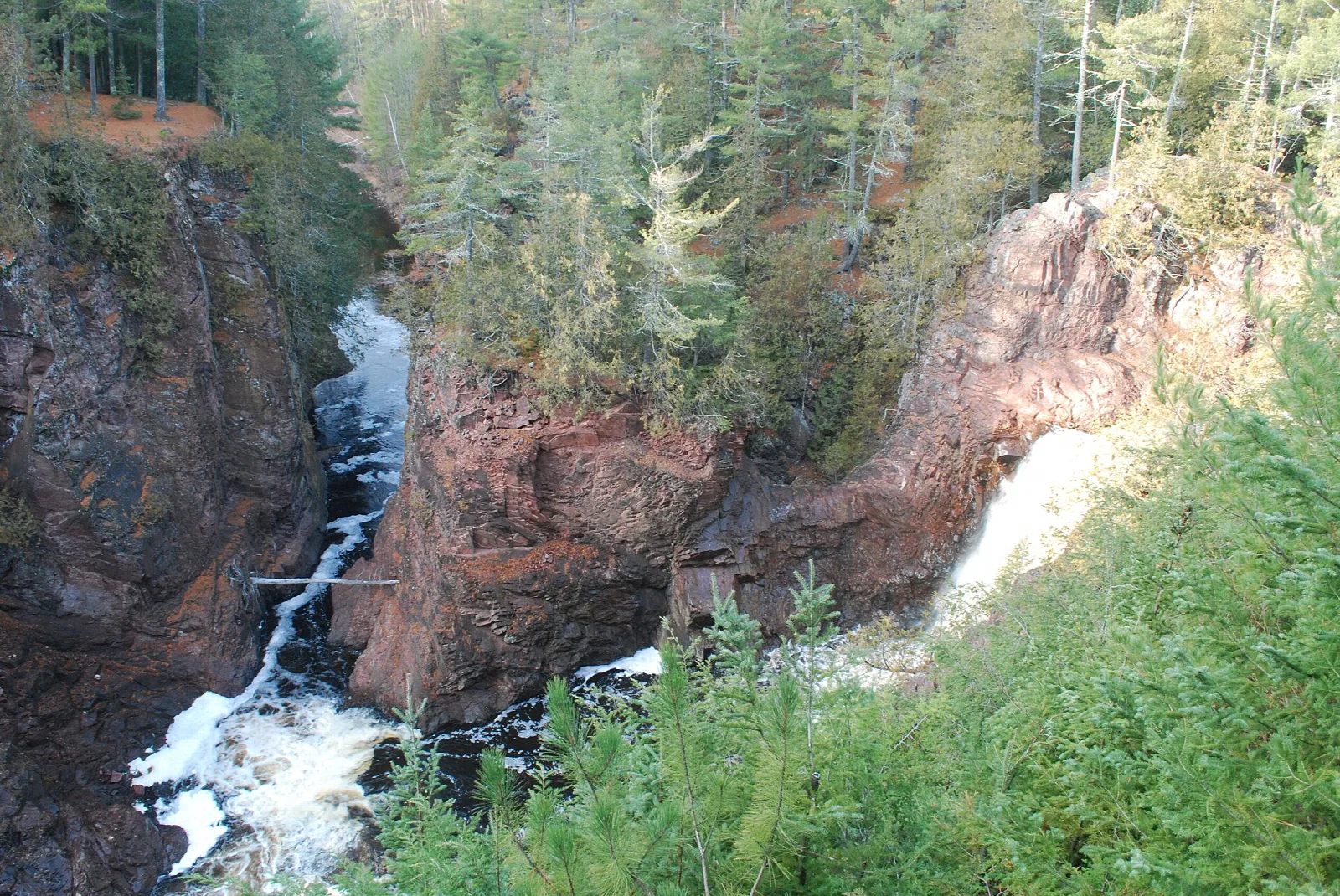 Narrow rocky gorge with a waterfall and forested rim