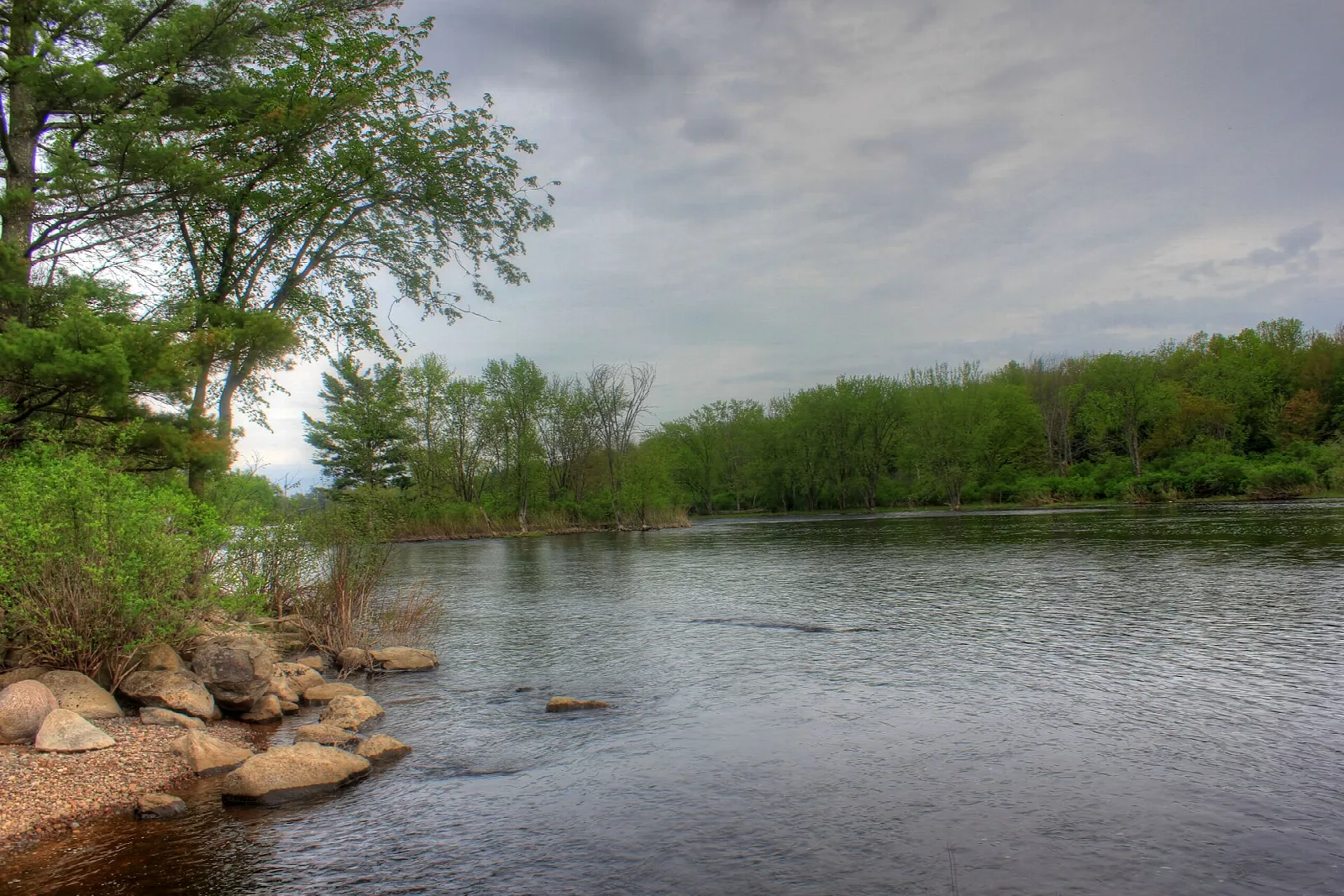 Rocky shoreline and calm water under a cloudy sky