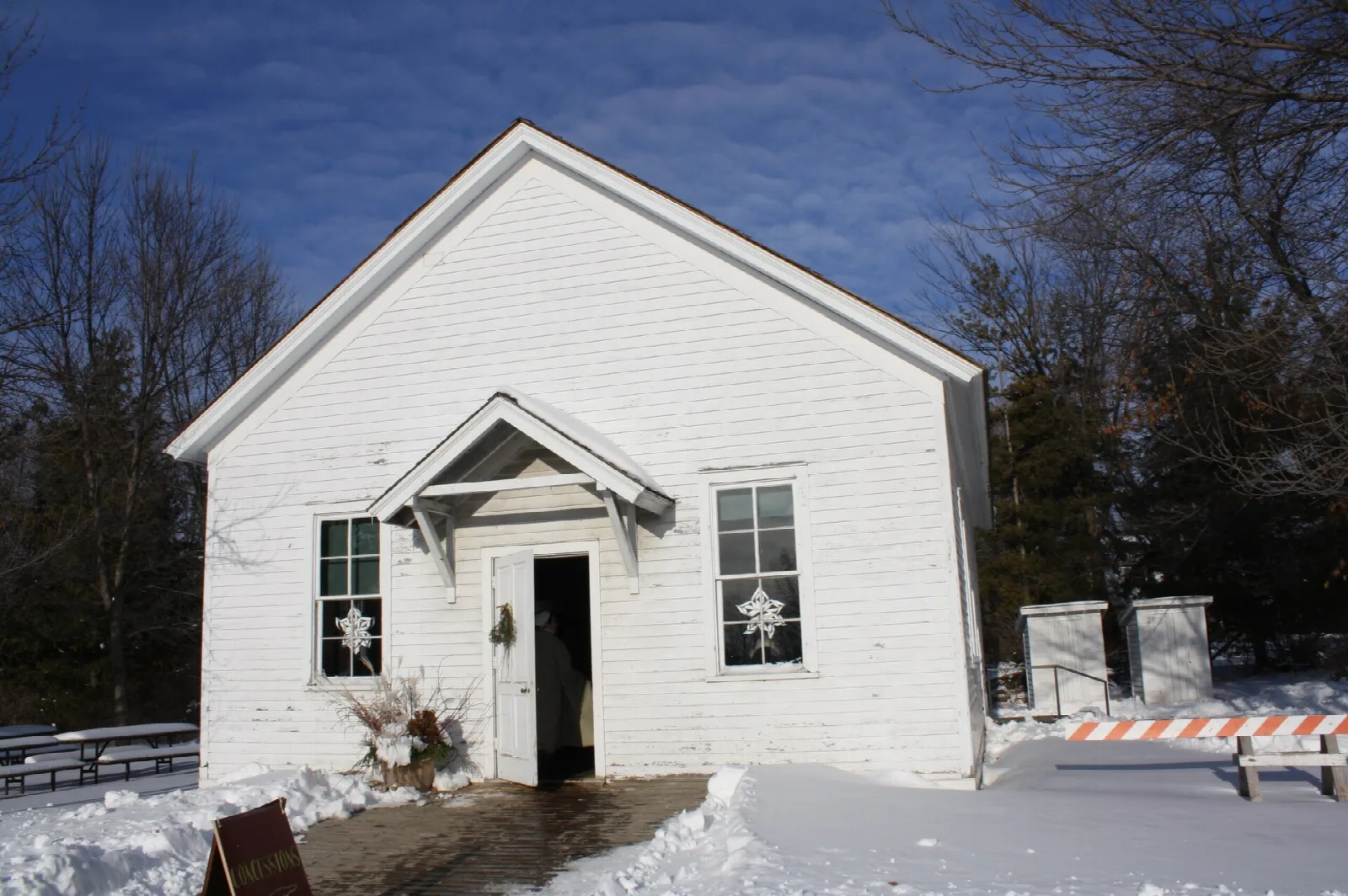 Small white one-room building with a gabled front porch in snow