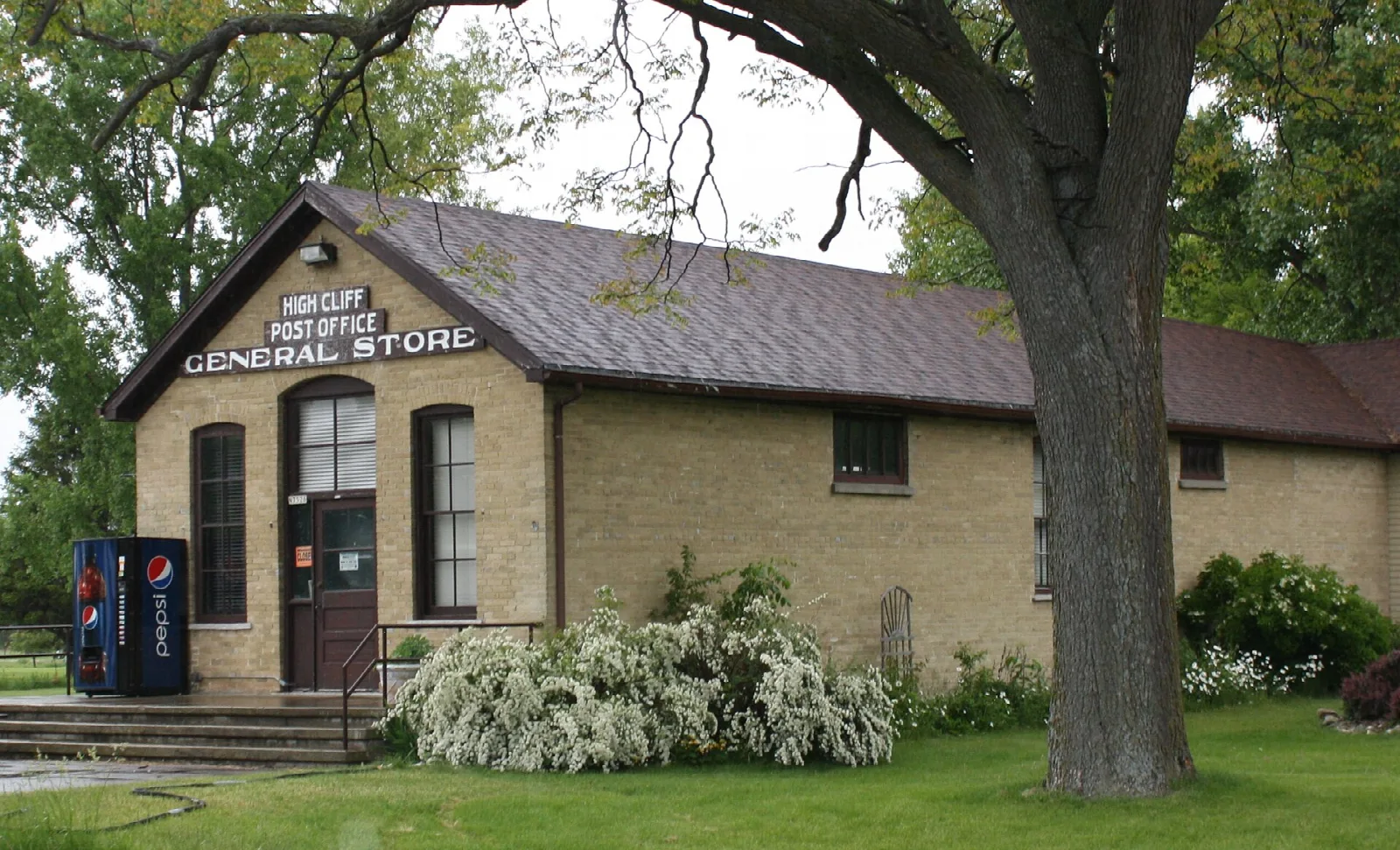 Tan brick general store and post office under a large tree