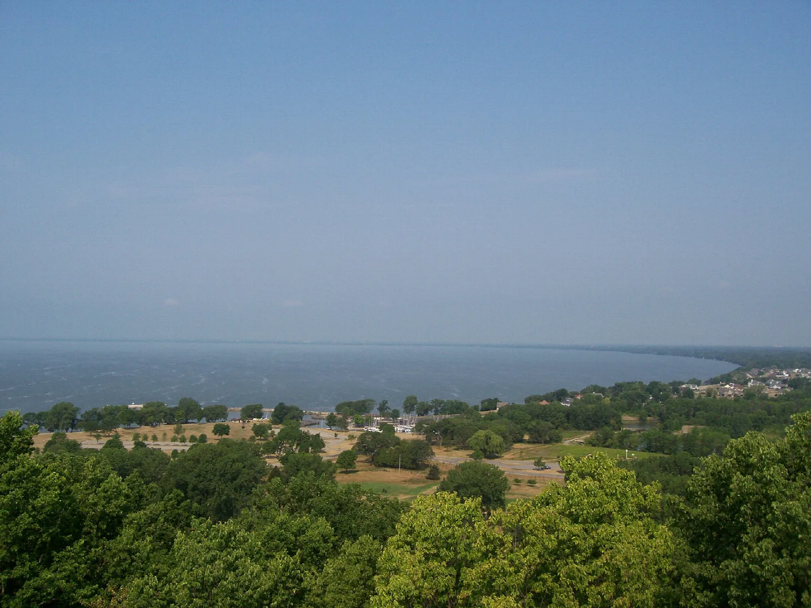 Wide lake seen over green treetops from a high lookout