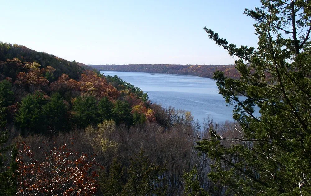 Wide river bend seen from a wooded bluff with autumn color on the hills