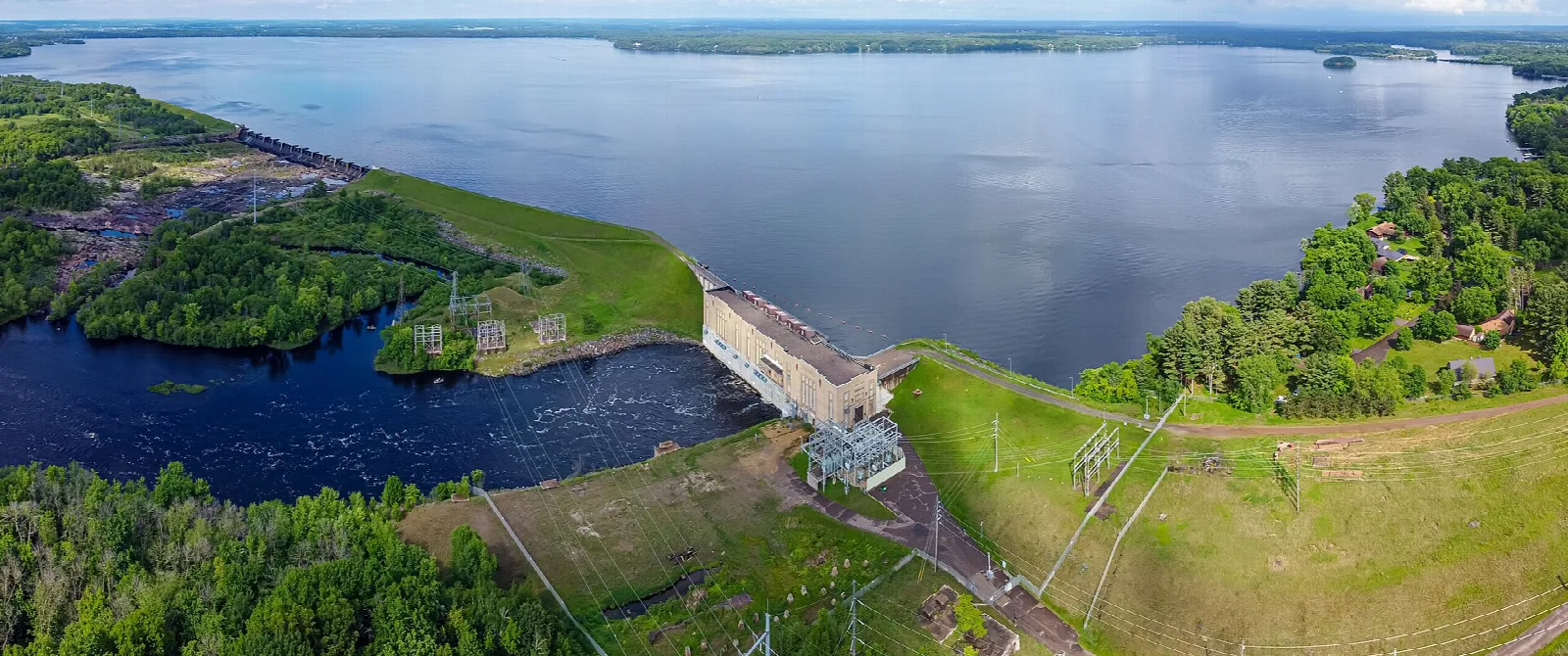 Aerial view of a wide lake, a dam and green shoreline