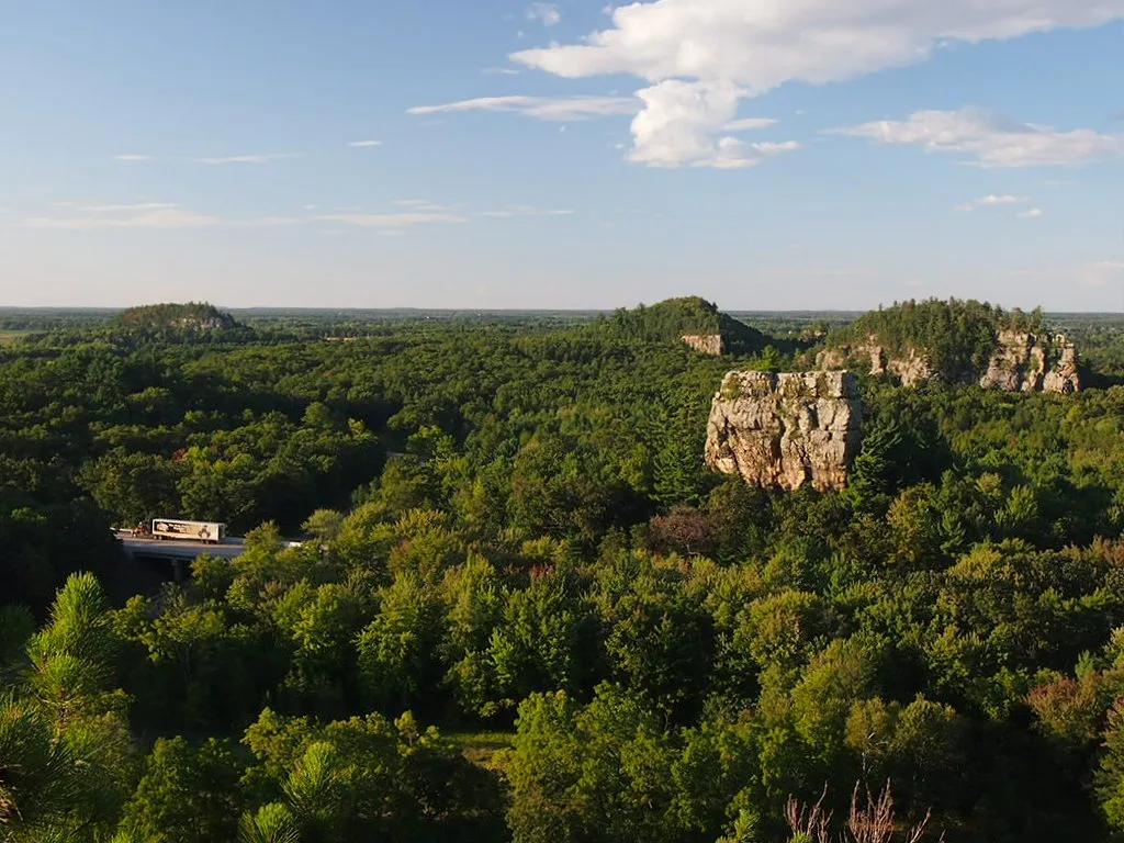 Rock bluff rising above a sea of green forest under blue sky