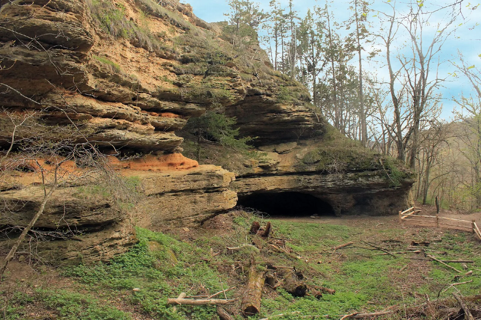 Orange sandstone cliff with a shallow cave opening at its base