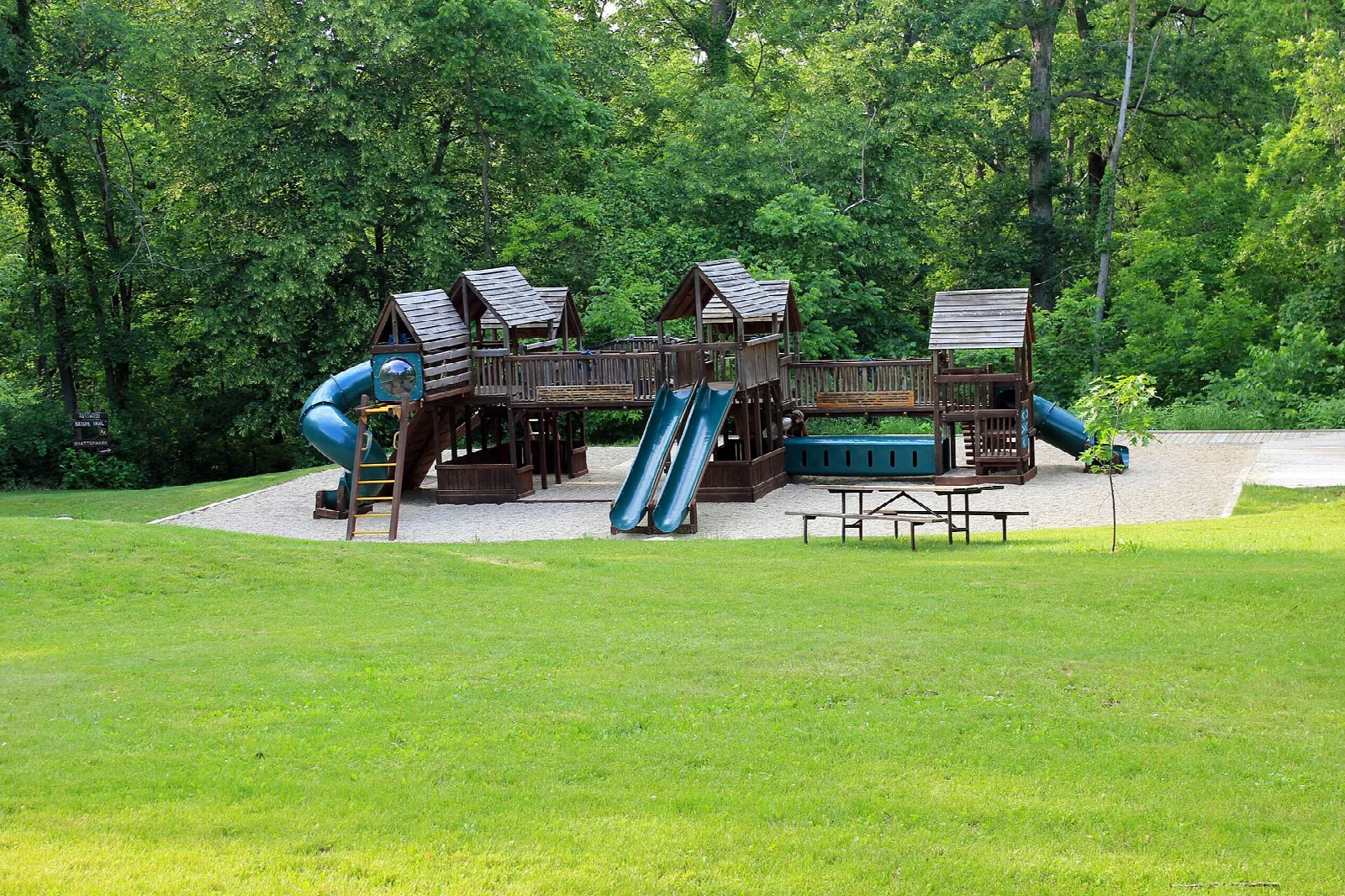 Wooden playground with slides on a mown lawn among trees