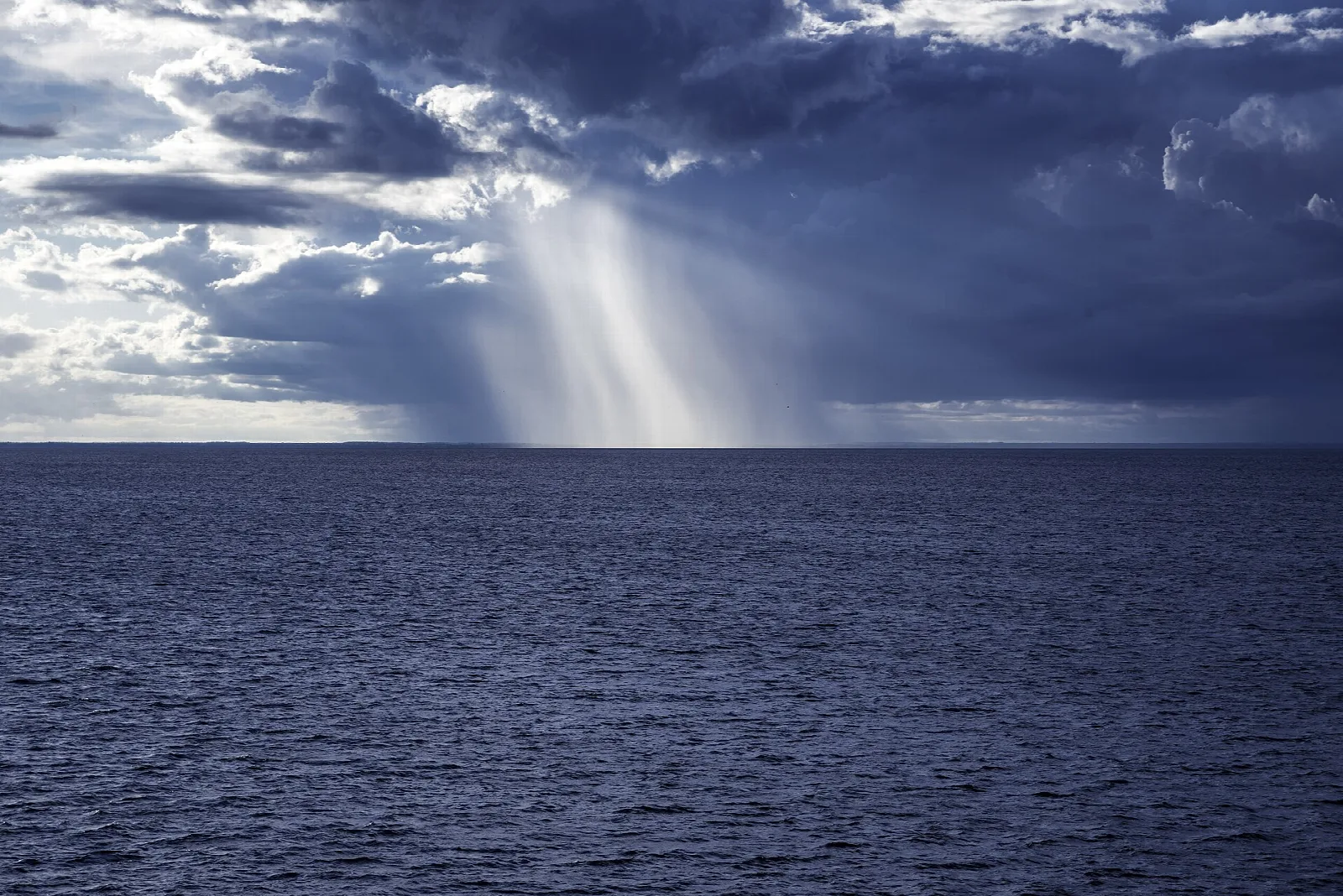 Rain falling from dark clouds over the open water of Lake Michigan