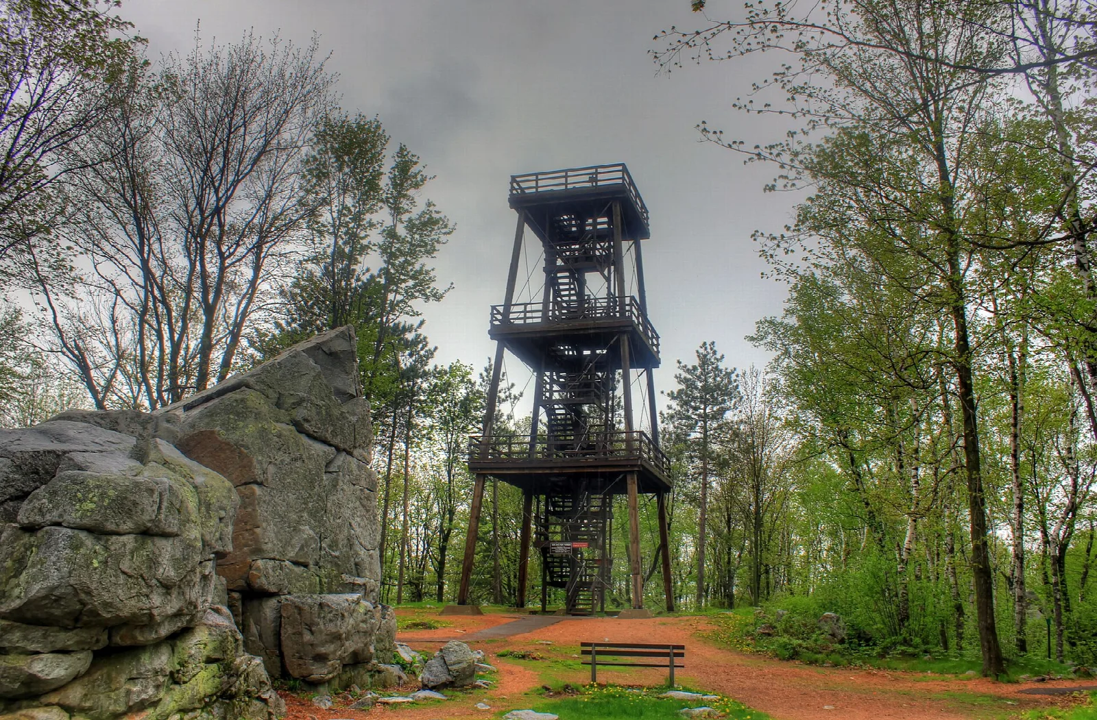 Metal observation tower rising above a rock outcrop and trees