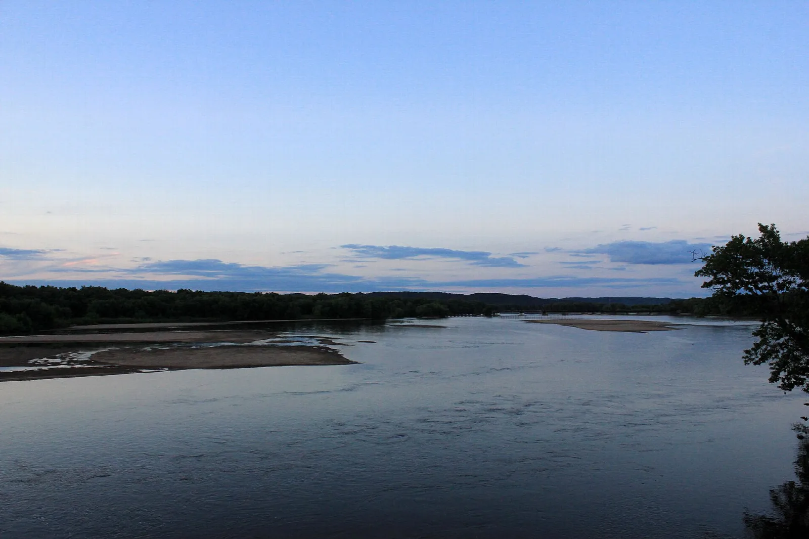 Wide river with sandbars under a pale evening sky