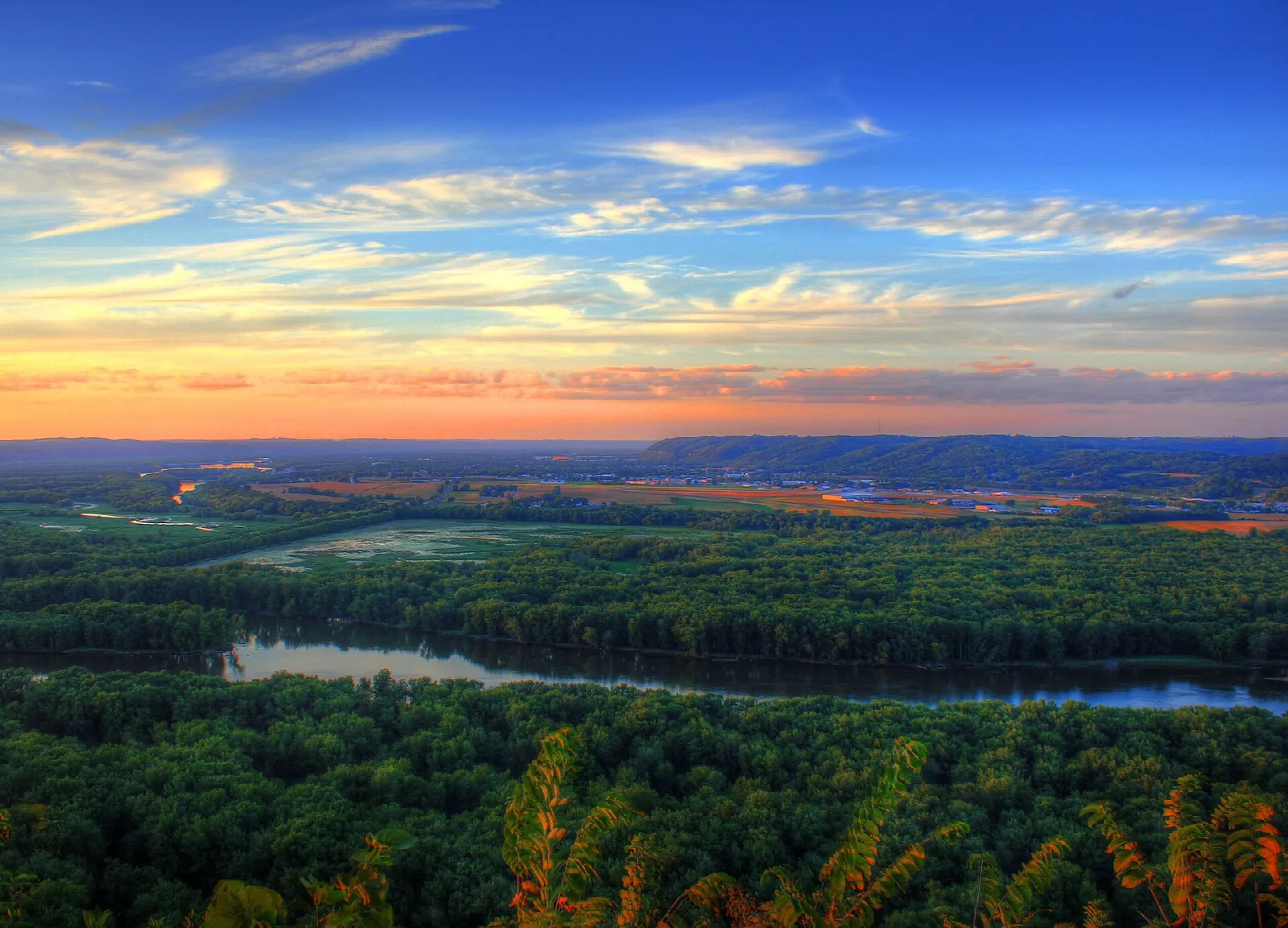 Sunset colors over a forested river valley seen from a bluff