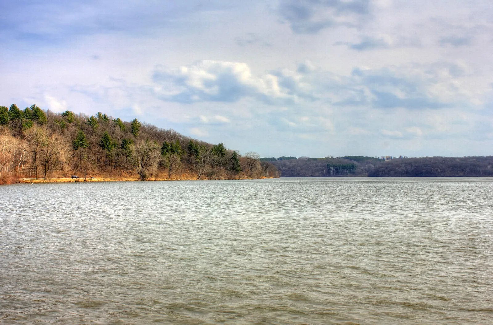 Wide lake with a wooded shore and a cloudy sky