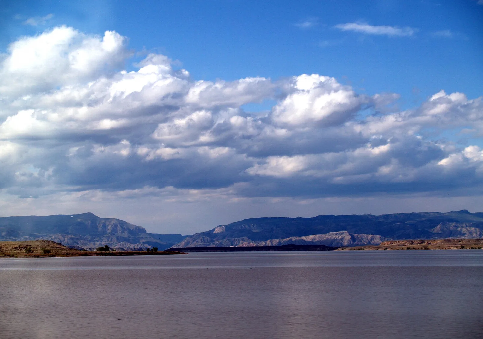 Wide reservoir under big clouds with low cliffs on the far shore