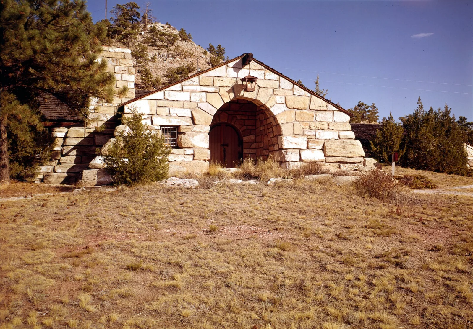 Stone museum building with an arched doorway on a dry grassy hill