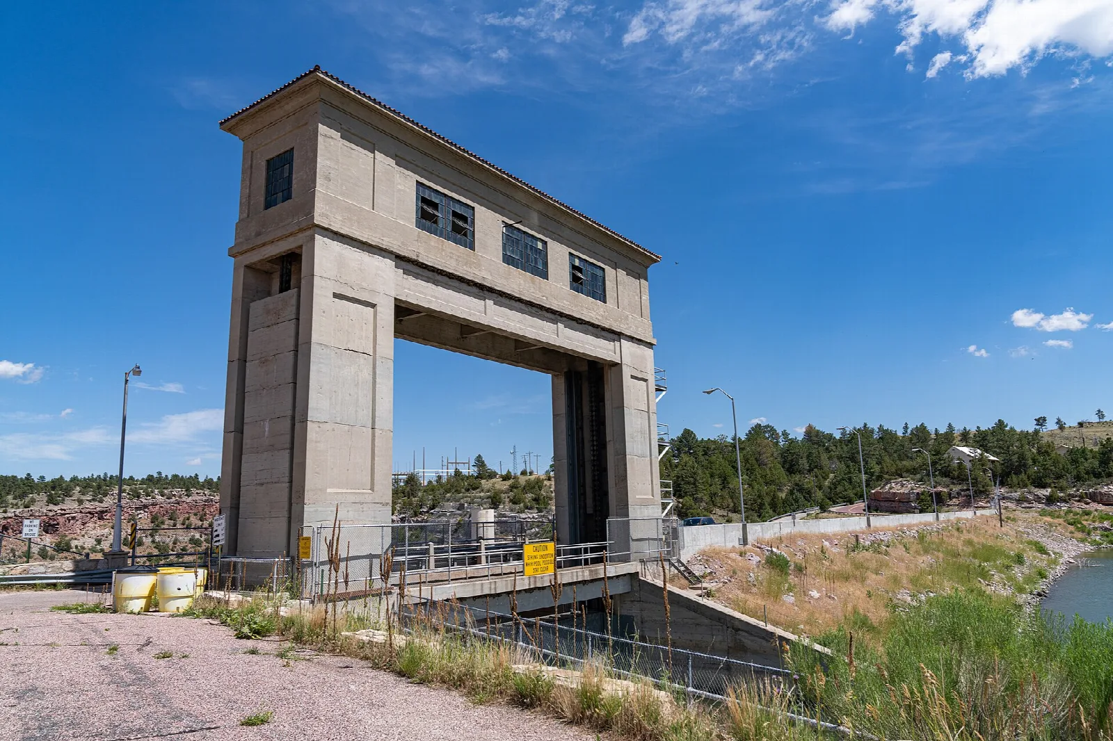 Tall concrete control tower over the dam spillway under blue sky