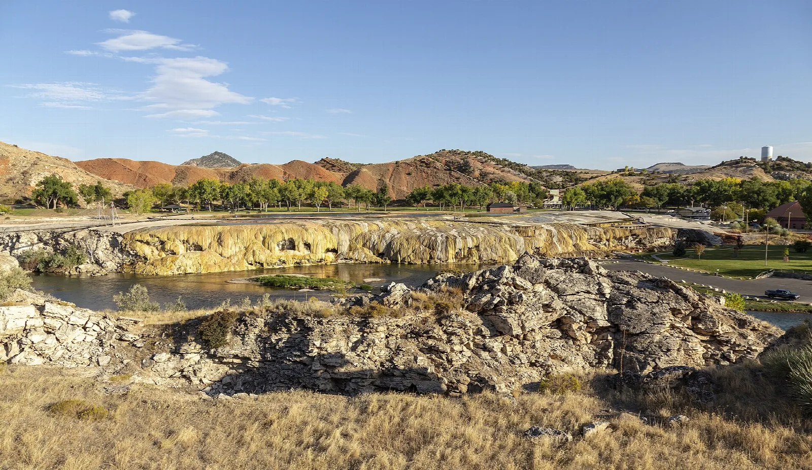 Travertine terraces along the river with red hills beyond