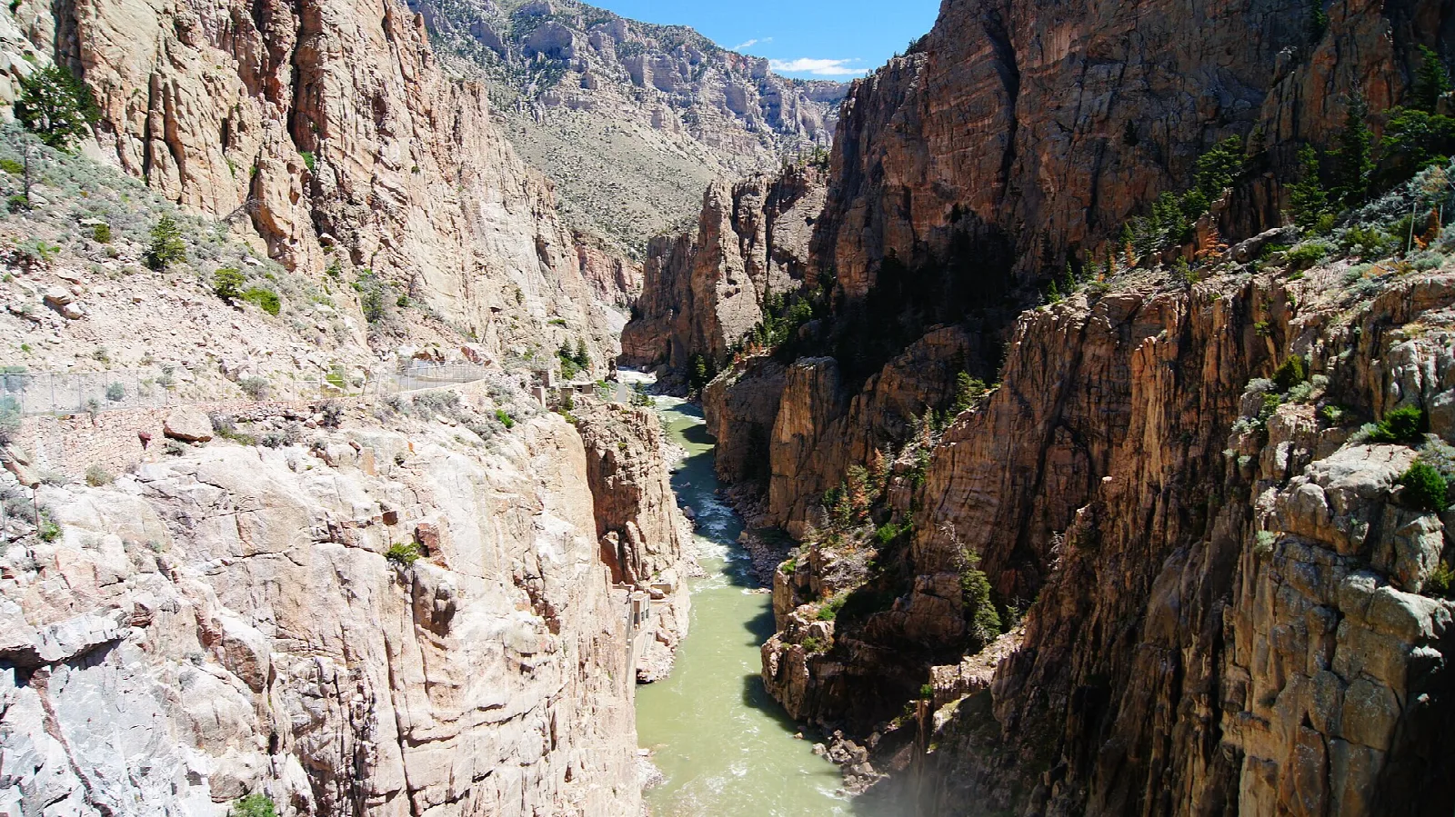 Narrow red rock canyon with a green river below