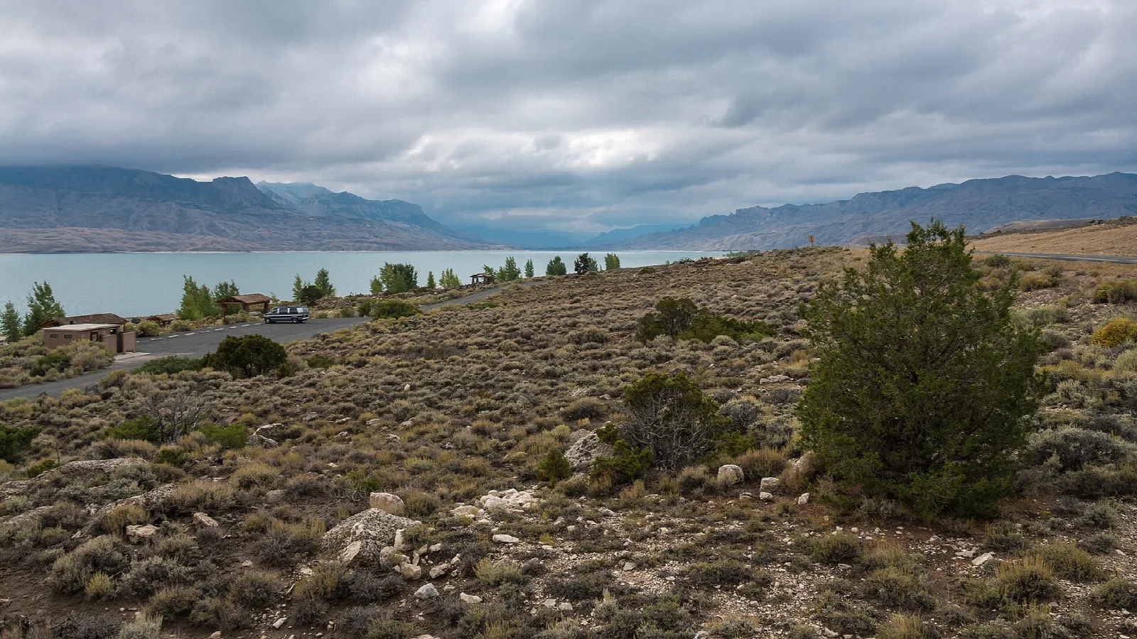 Reservoir under cloudy sky with sagebrush hills in front