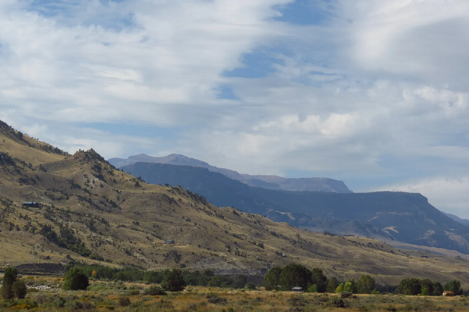 Brown hills and a ridge under a partly cloudy sky