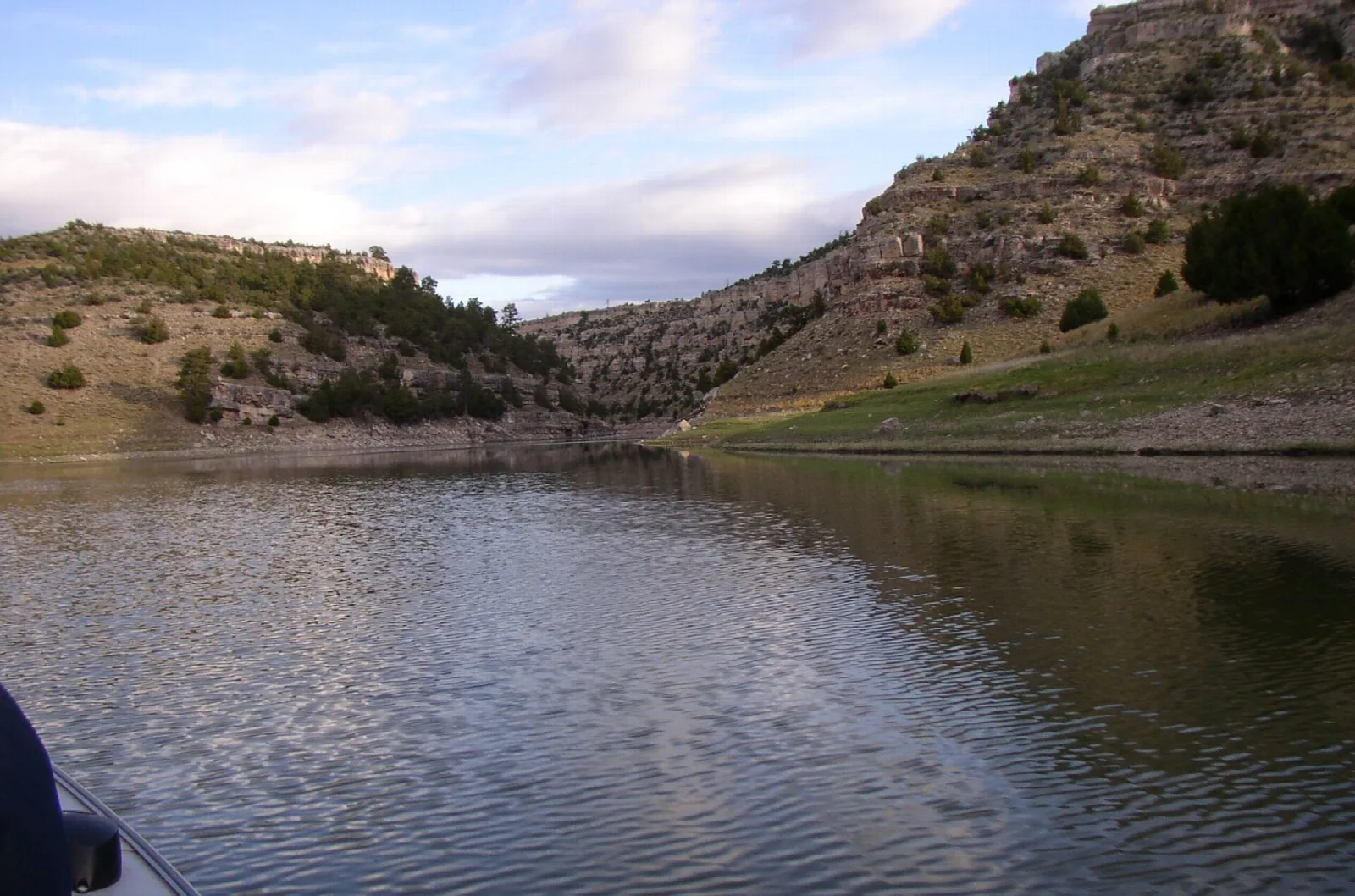 Calm river water below a rocky hillside