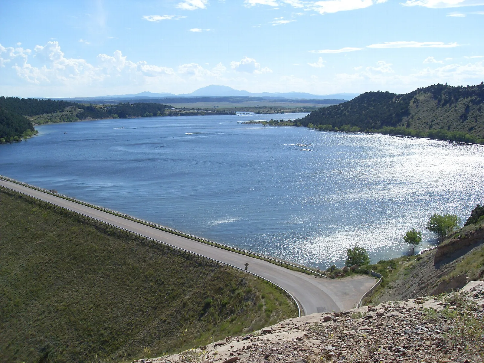 Reservoir with a distant peak behind it and a road along the dam
