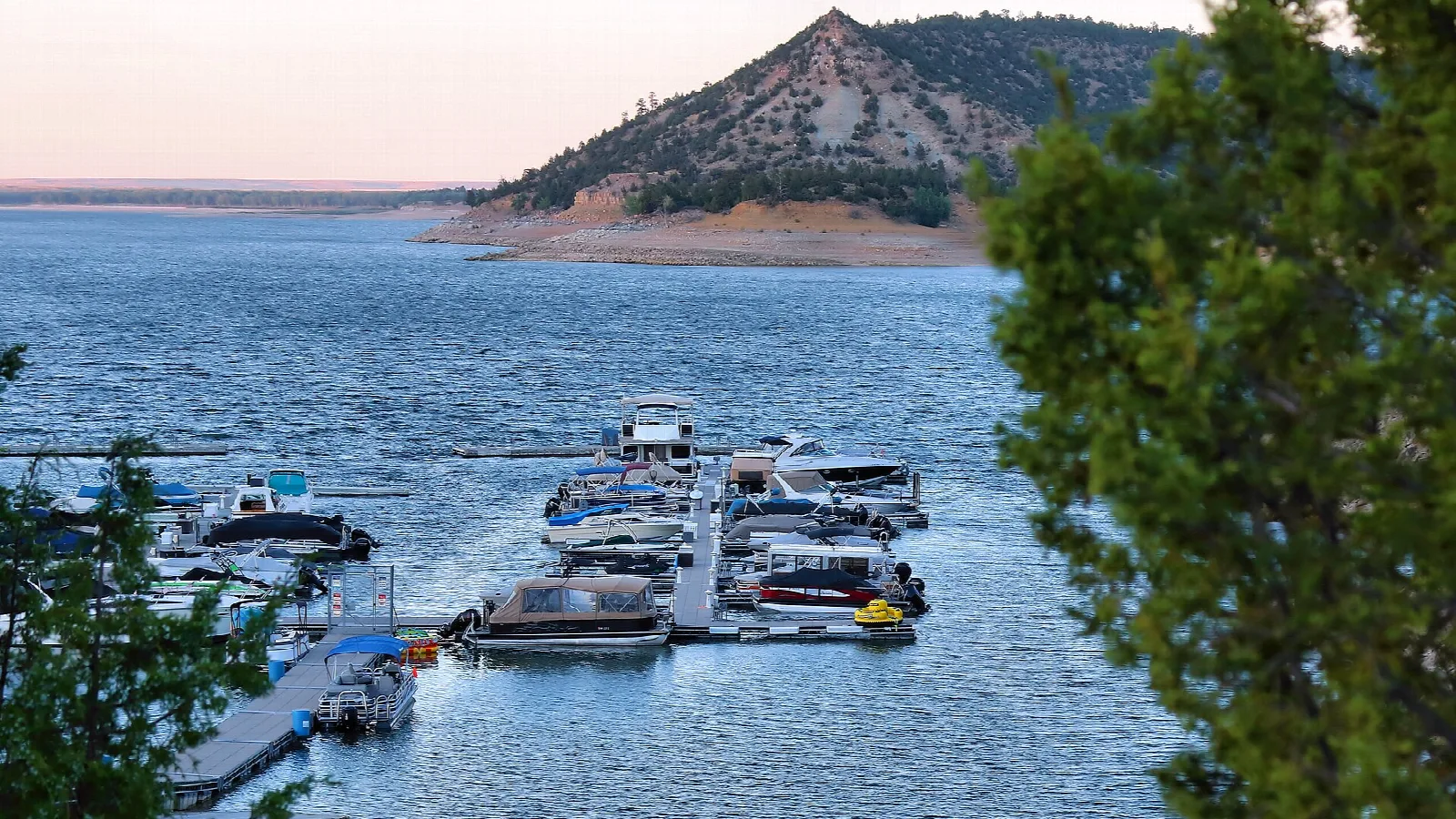 Boats docked at a marina below a rocky hill