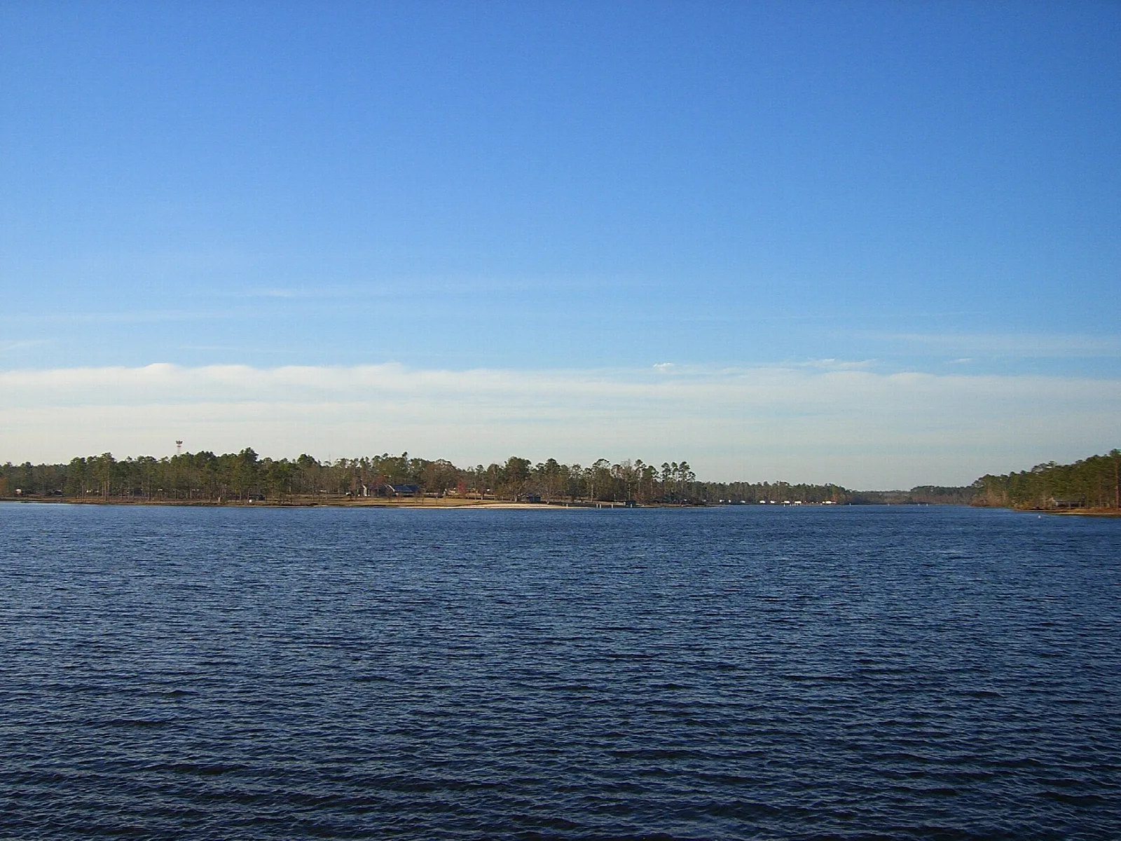Wide lake under a blue sky with a low tree line on the far shore