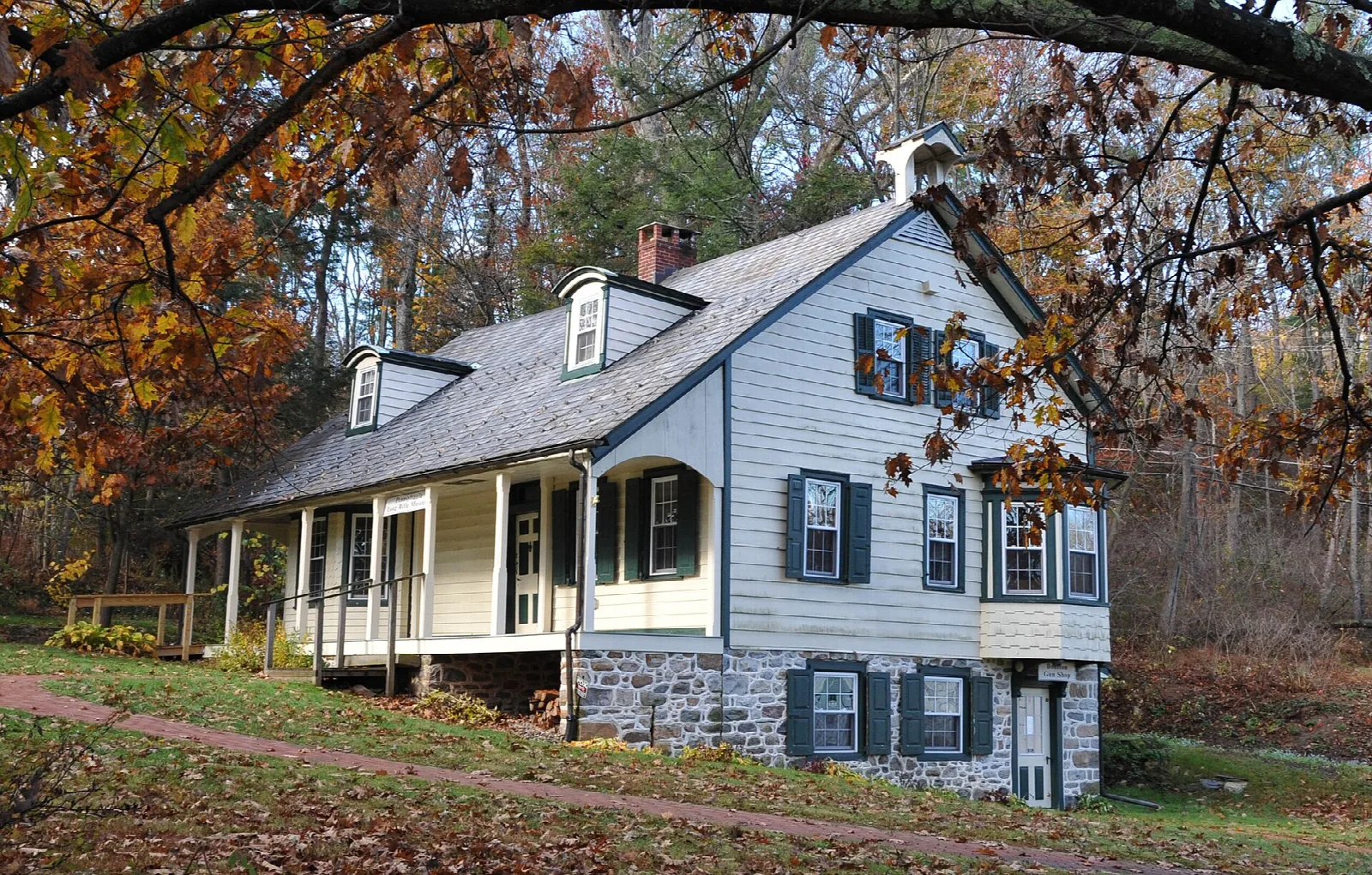 White farmhouse with a porch among fall trees