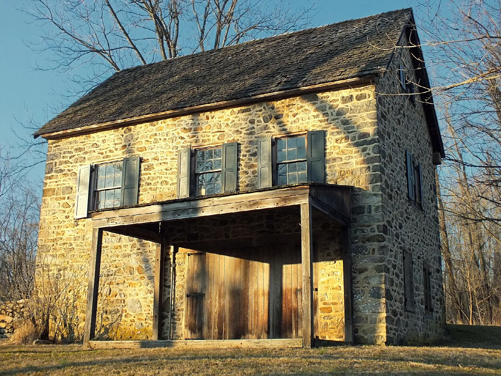 Stone building with a wooden porch in a field