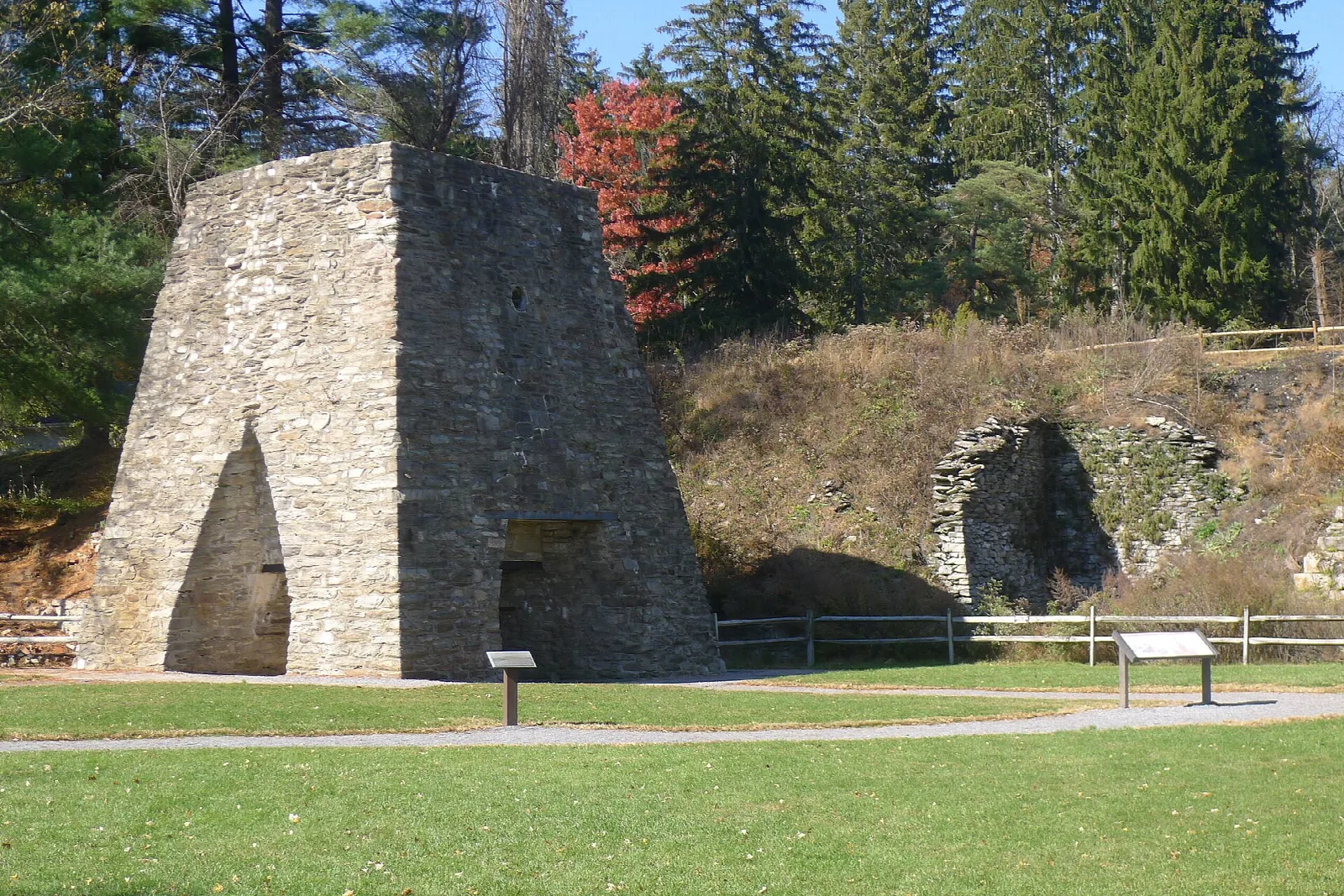 Tall stone furnace stack beside a mown lawn