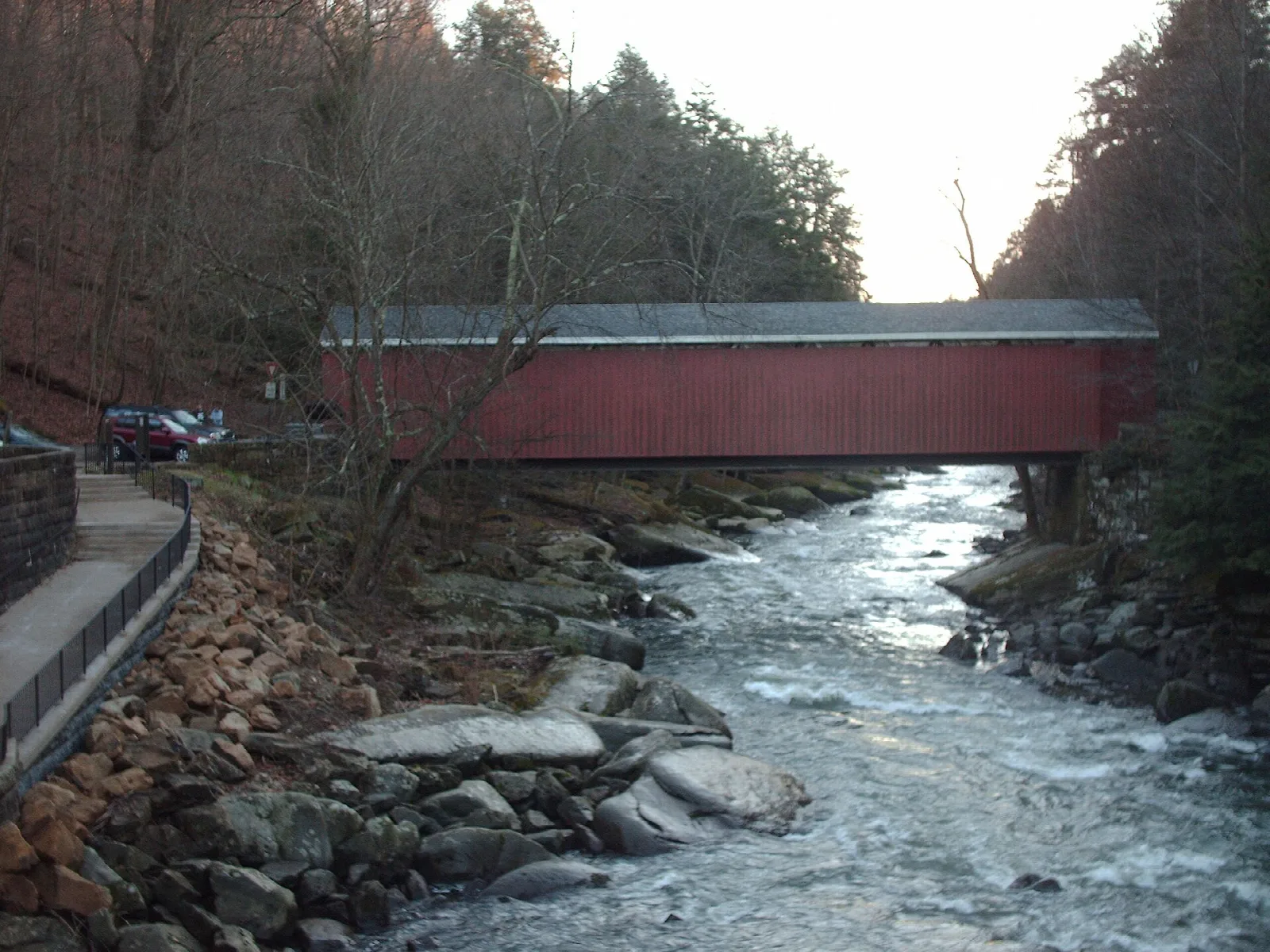 Red covered bridge above a rocky creek in a wooded gorge