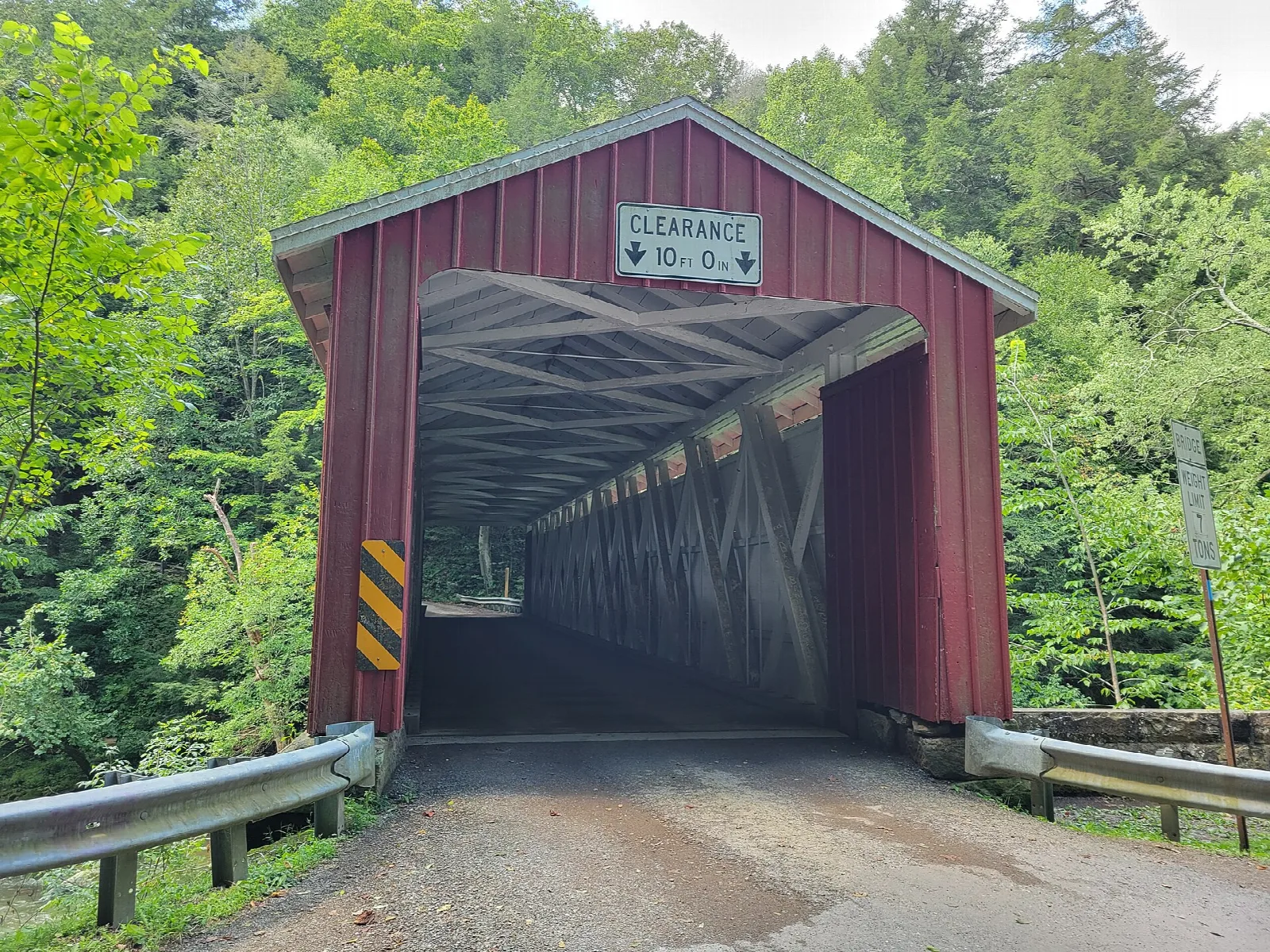 Red covered bridge with a gravel road through it