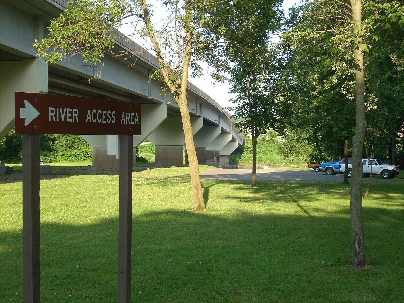 Concrete bridge beside a green lawn with a river access sign