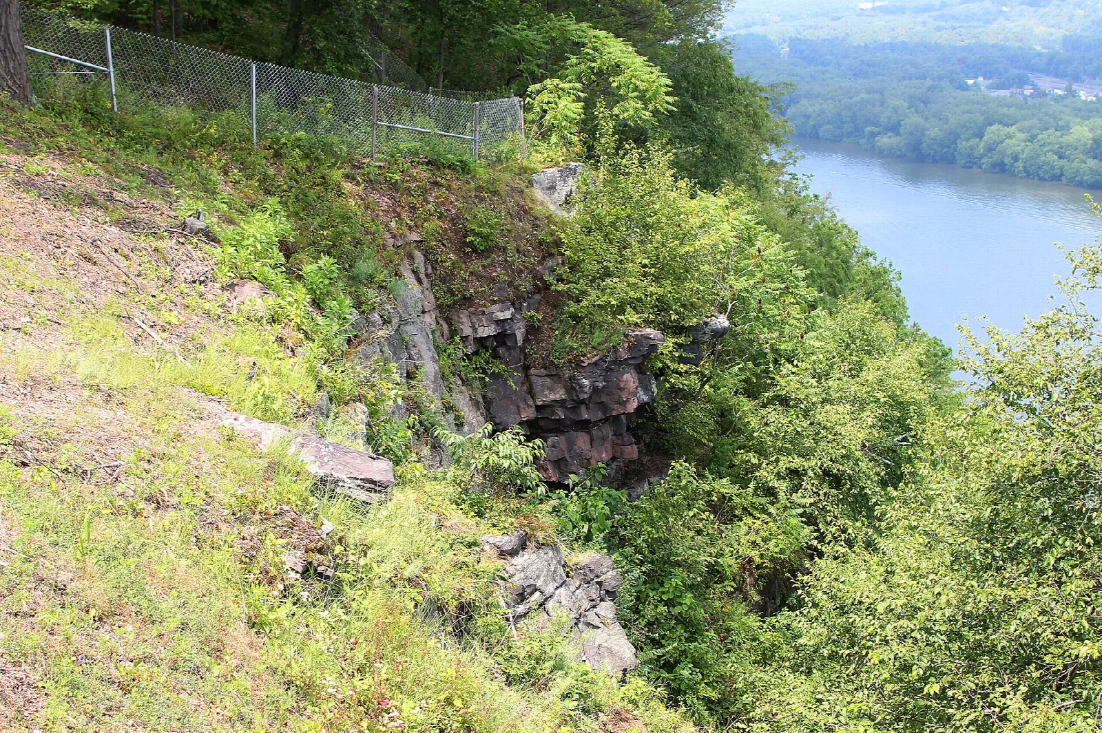 Rocky cliff edge above the river behind a fence