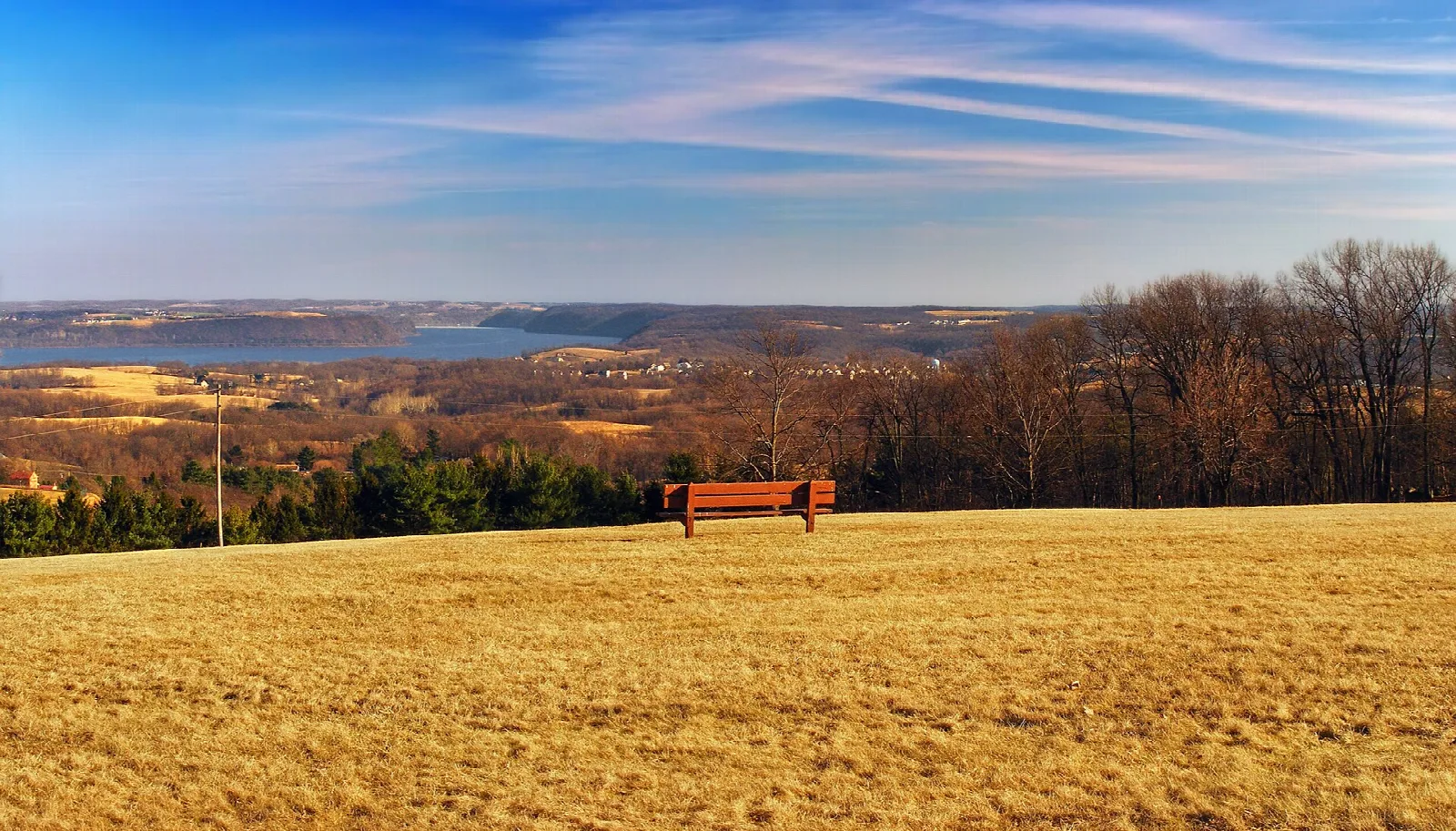 Golden grass hillside with a red bench and a valley view
