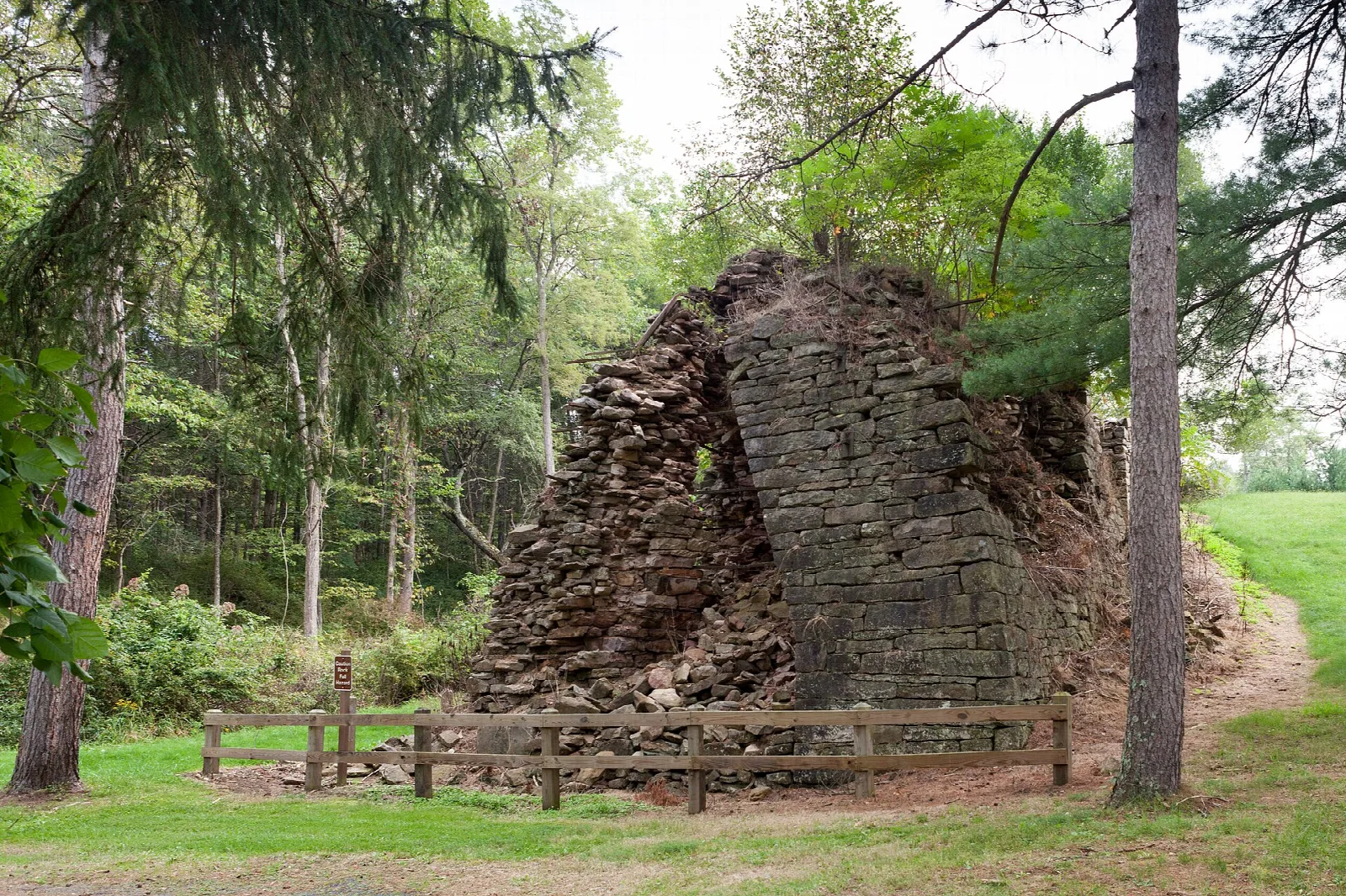 West side of an old stone furnace stack with trees around it