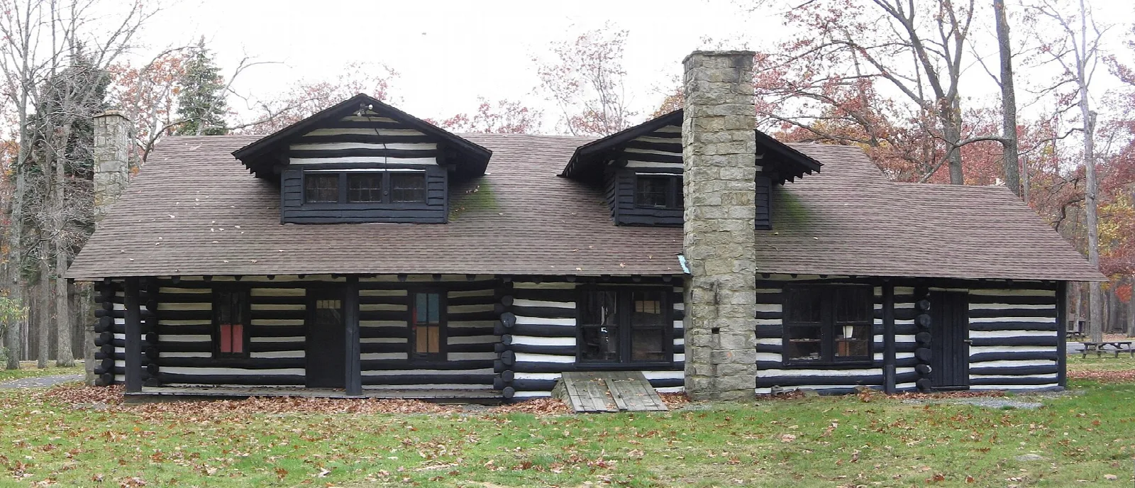 Rear of a long log lodge with a stone chimney