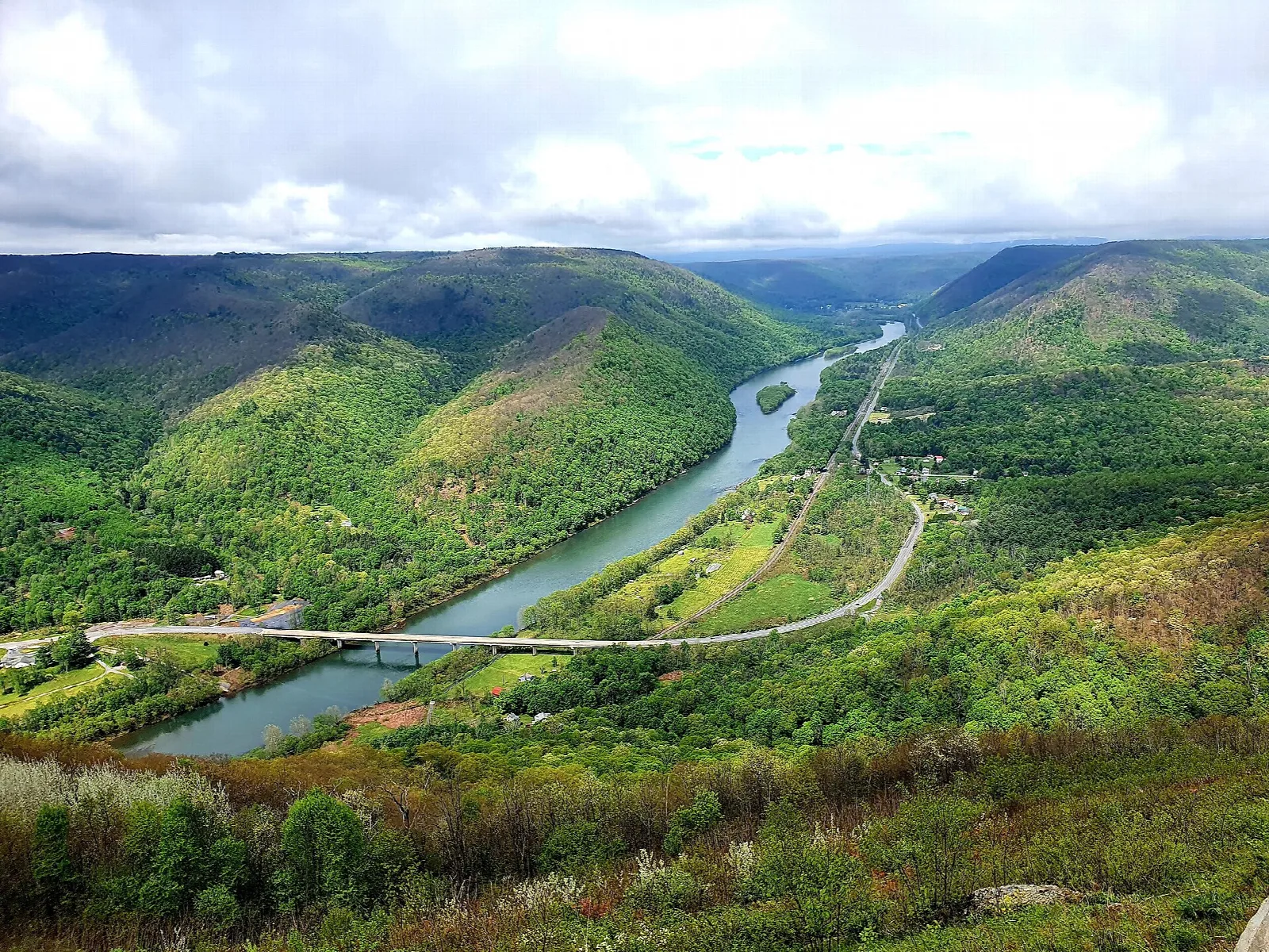 River and bridge in a green valley with rolling mountains