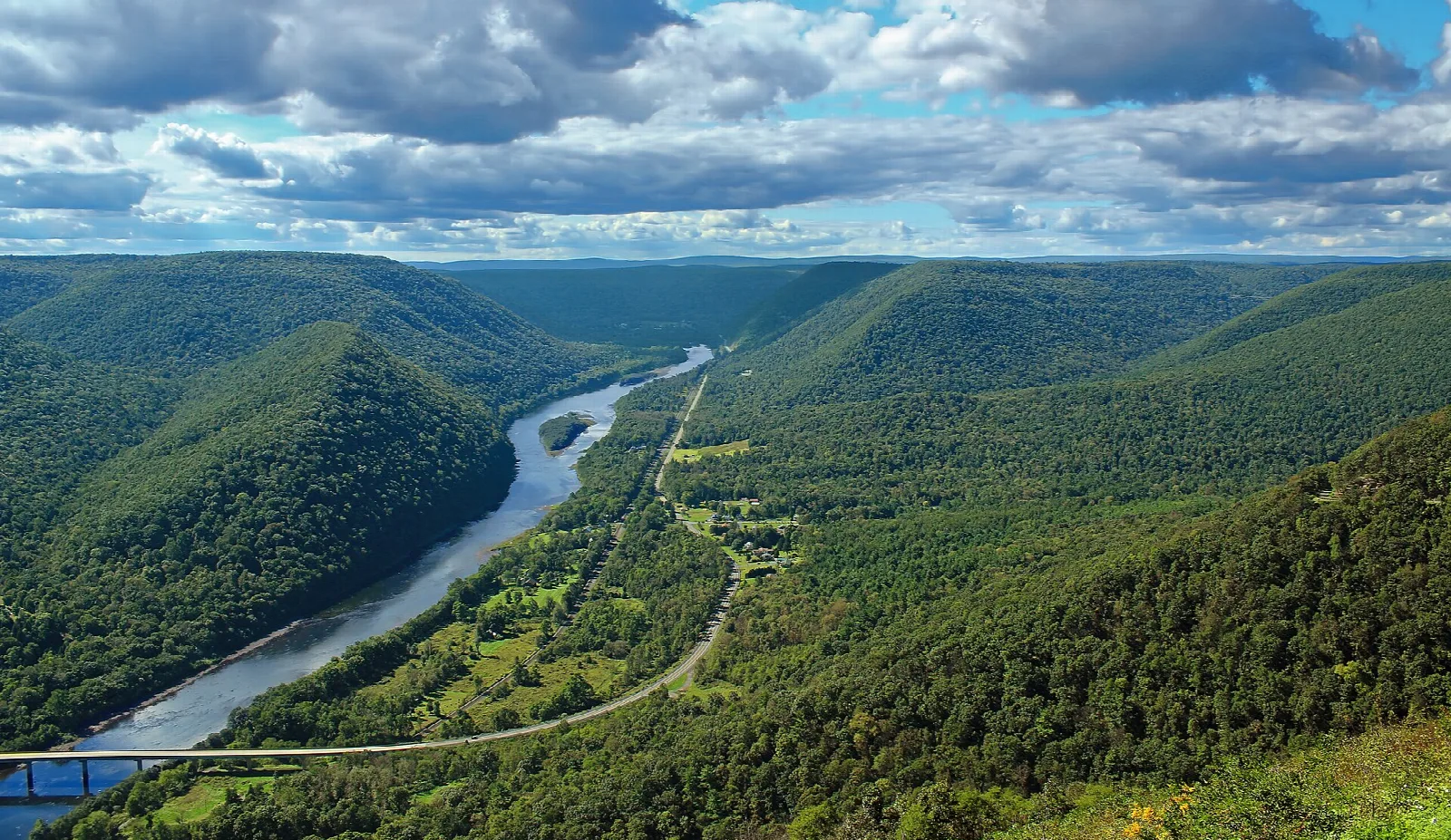 River winding through a deep forested valley under clouds