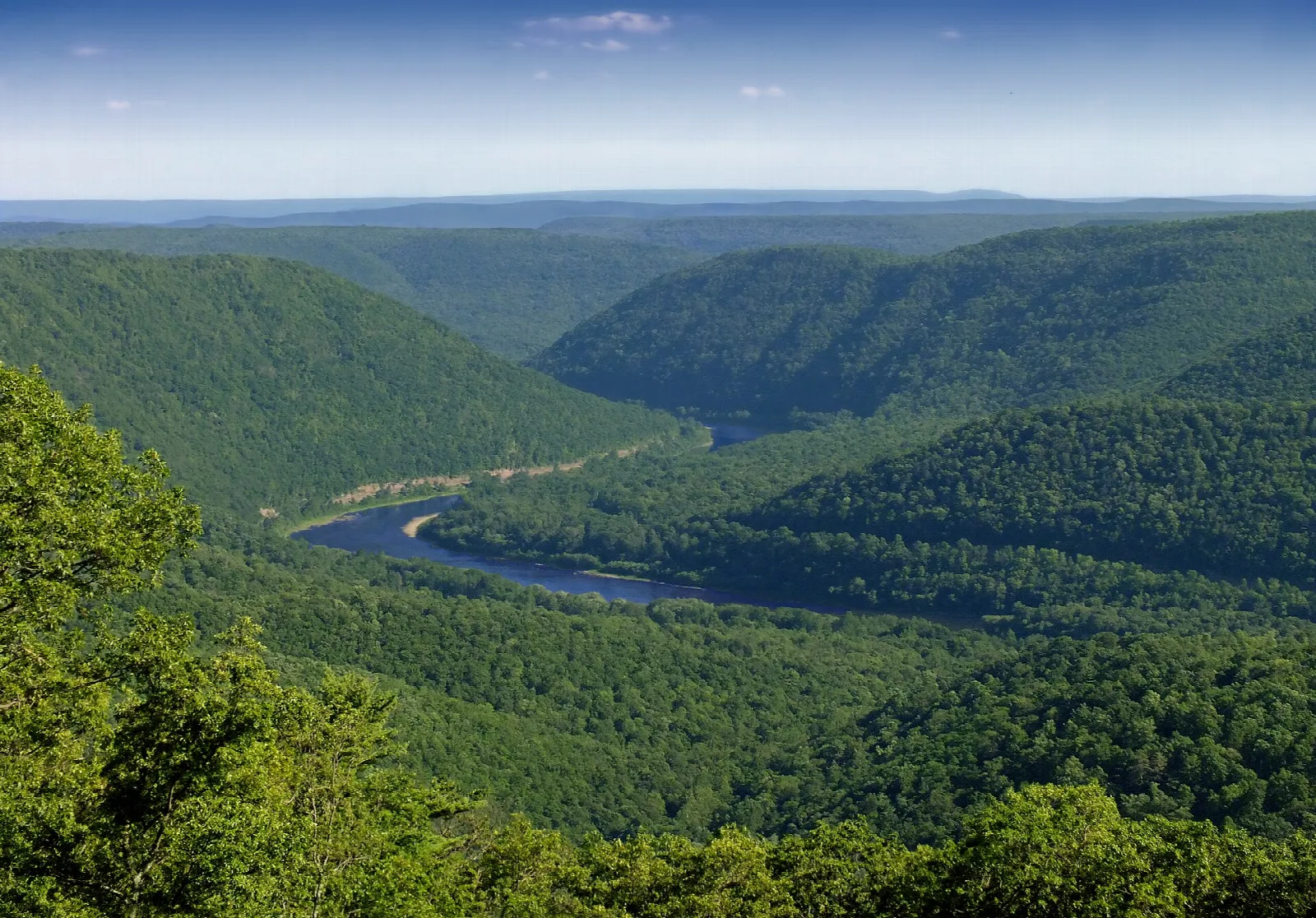 Forested mountains above a river valley with haze