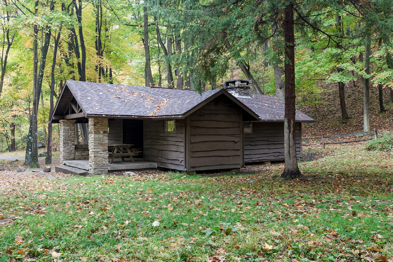 Low timber cabin with stone piers on a grassy lawn